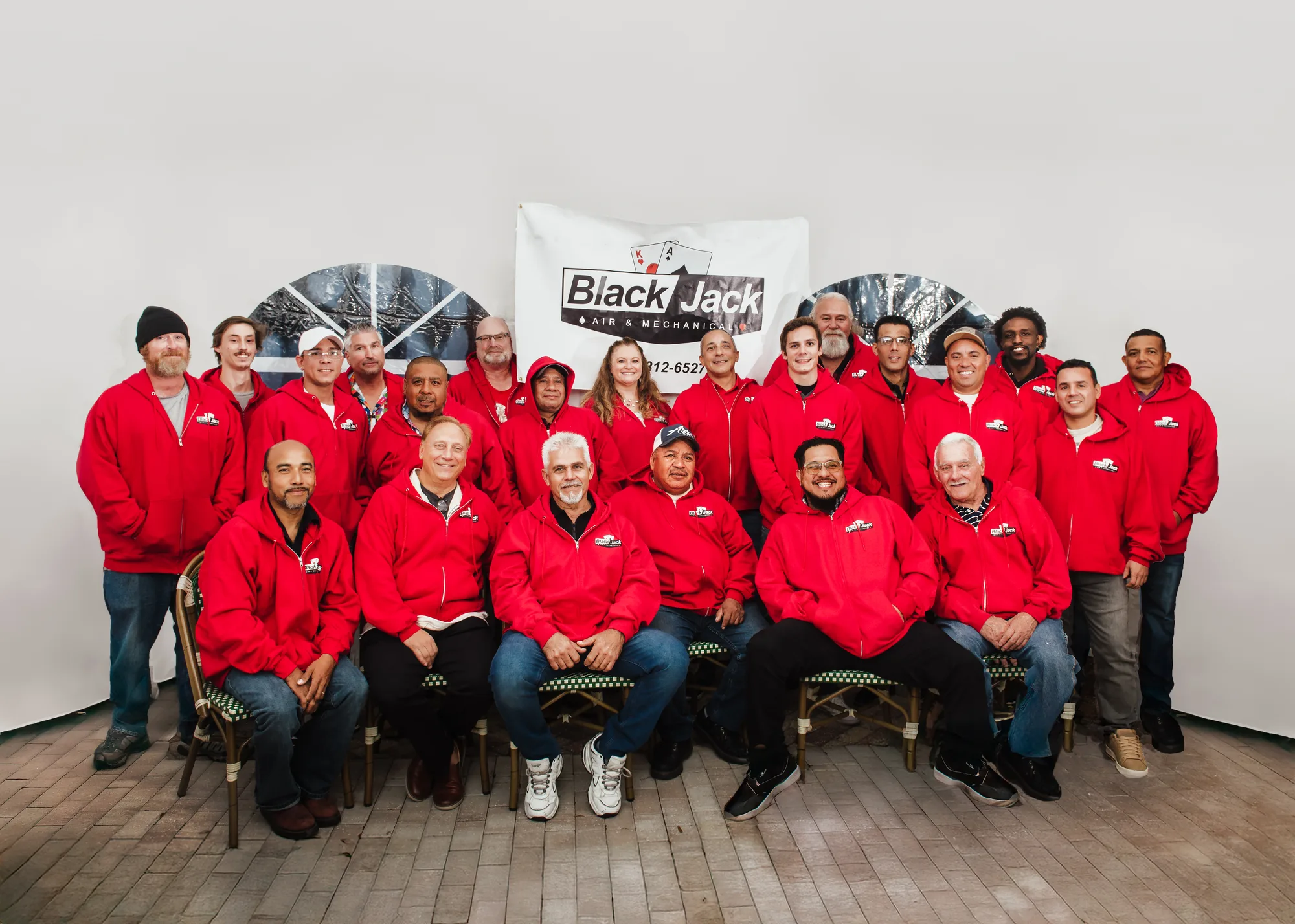 The Black Jack Air & Mechanical crew of about twenty-five in matching red company jackets, arranged in three rows for a group portrait.
