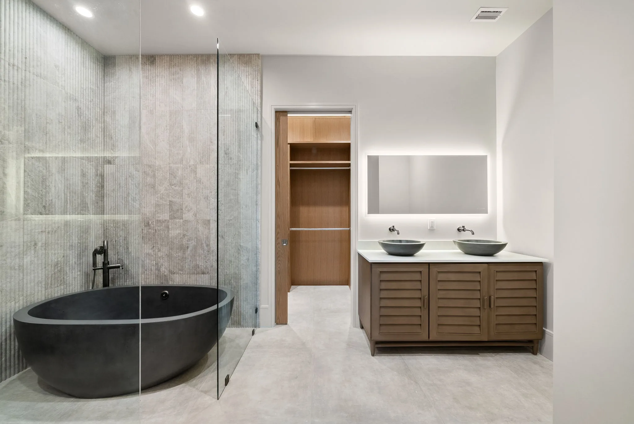 A bathroom with a freestanding black soaking tub beside a glass walk-in shower.