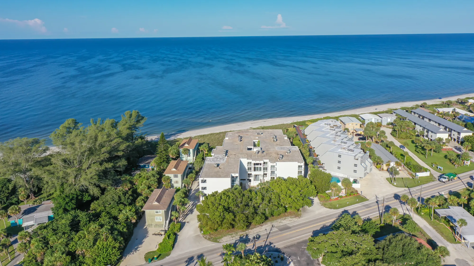 Aerial of The Surf Club buildings tucked among coastal vegetation on the Gulf shoreline.