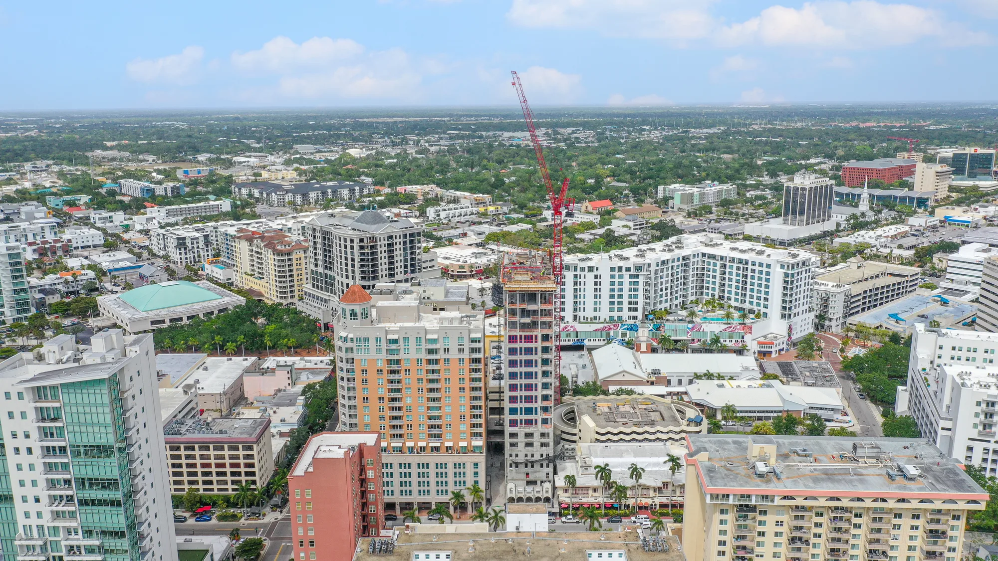 Aerial of downtown Sarasota with The DeMarcay tower under construction, a red tower crane above the site.