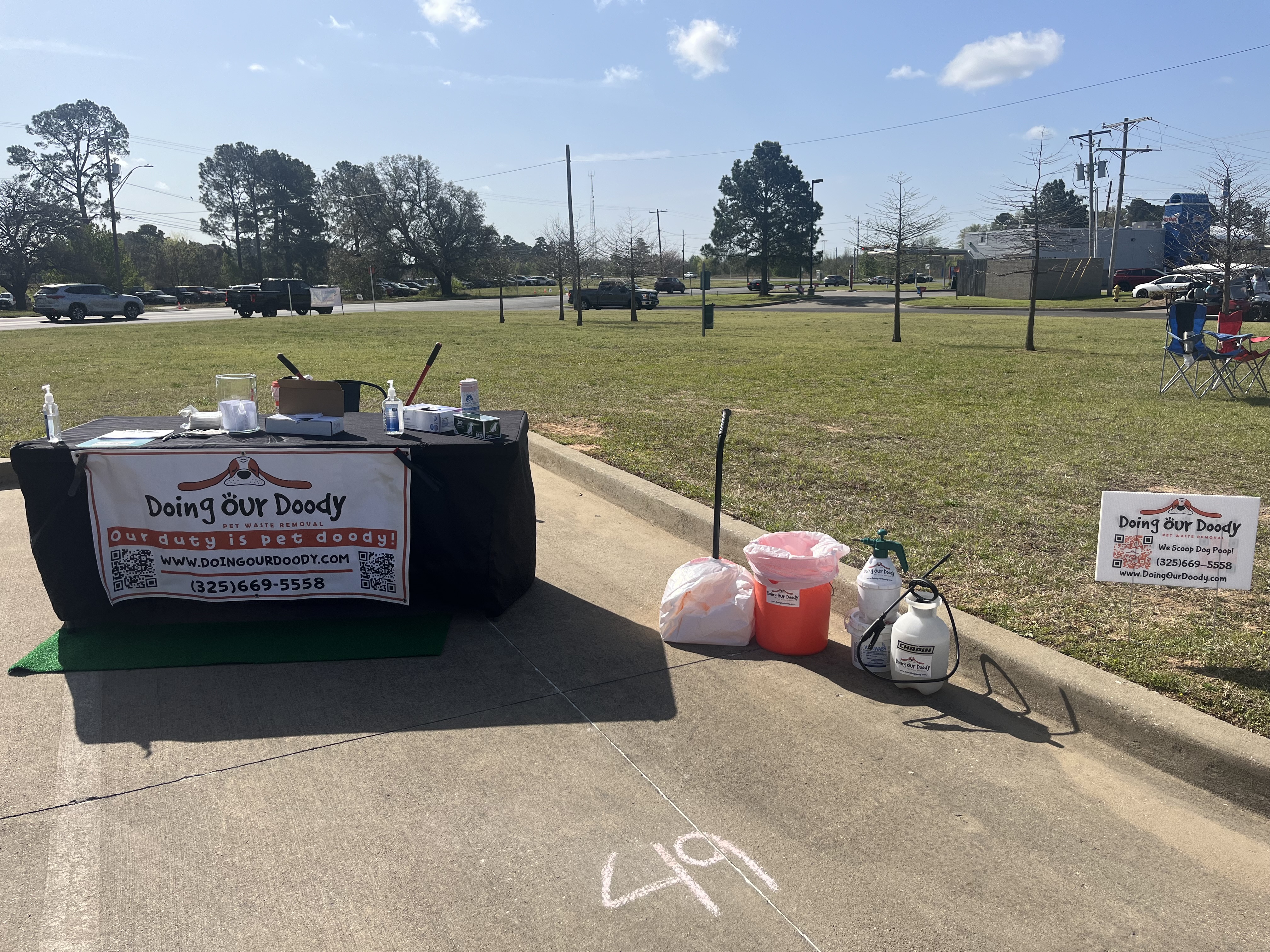 Doing Our Doody pet waste removal service booth with banner and cleaning supplies