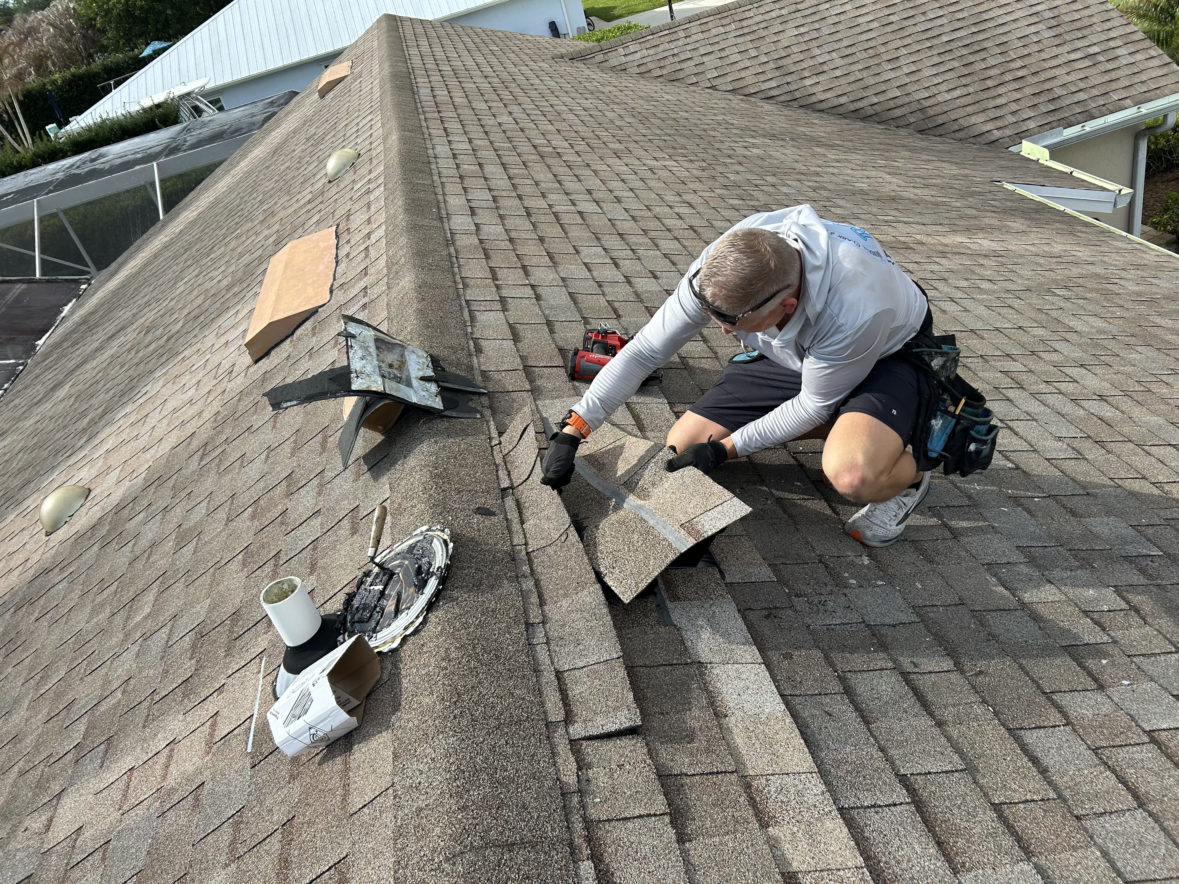 Roofer repairing shingles on a residential roof