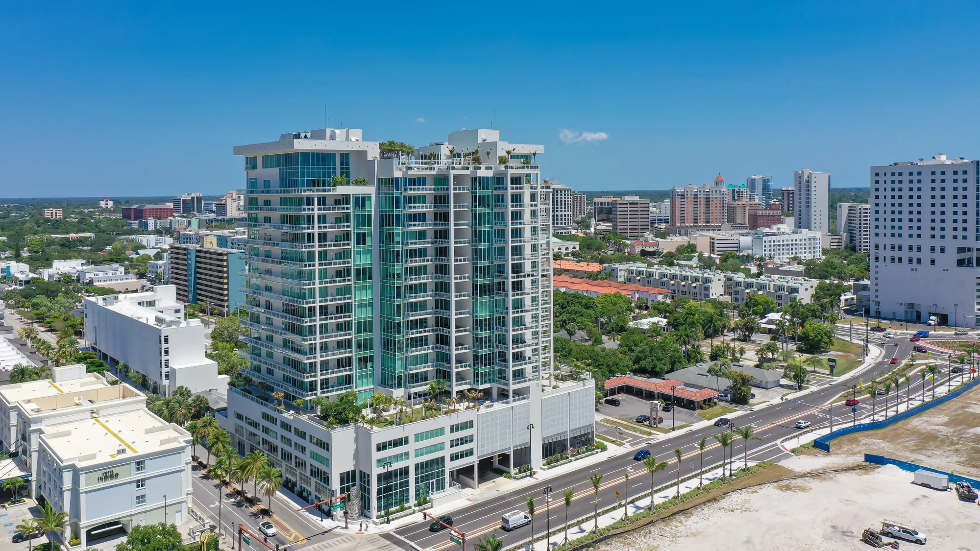 The Epoch tower seen from the air with the low-rise Sarasota skyline and treeline behind.