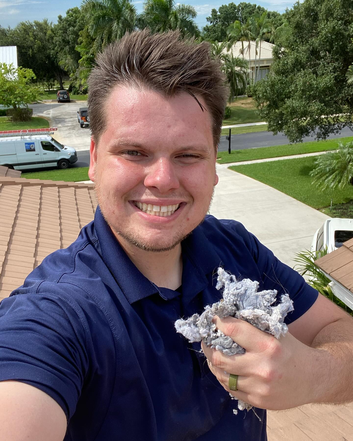 Dryer Vent Doctors technician on a roof holding debris removed during cleaning