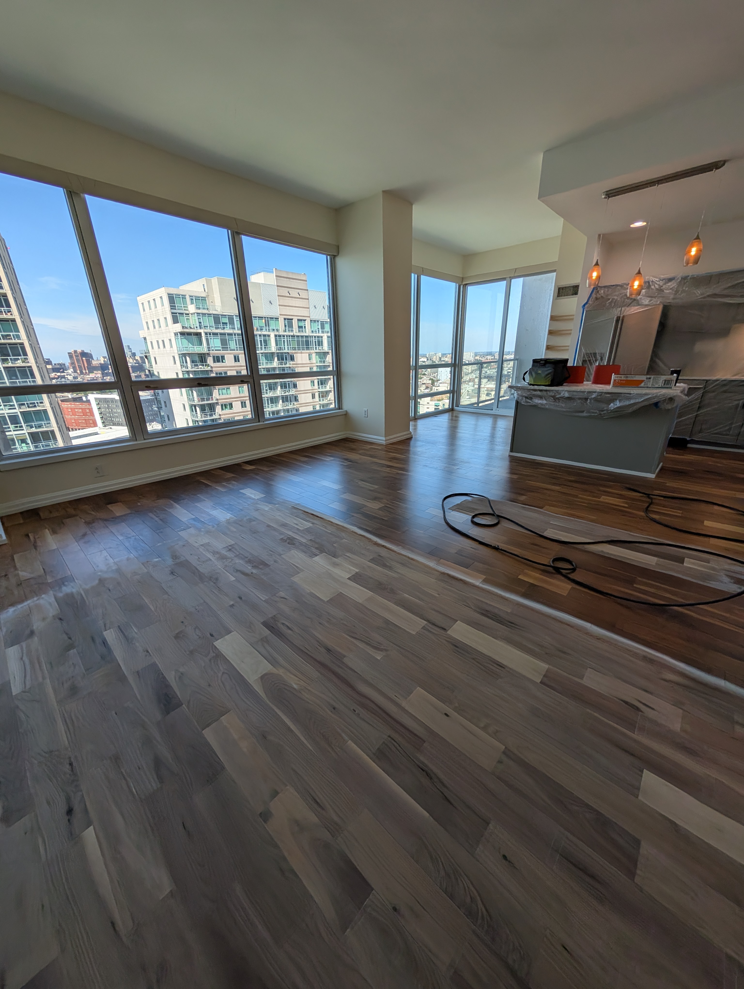 Spacious apartment interior with hardwood flooring in multiple shades during renovation