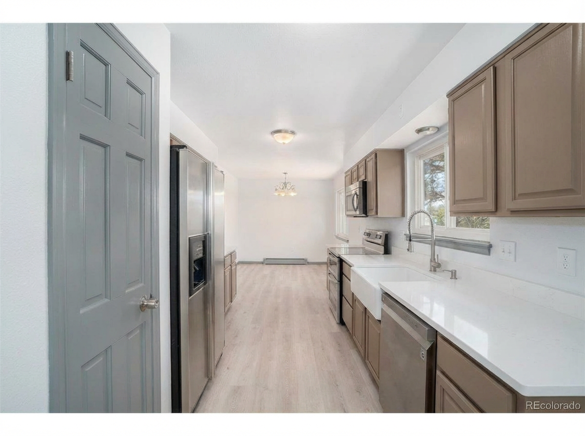 Modern kitchen with light-colored cabinetry, stainless steel appliances, and quartz countertops with natural light