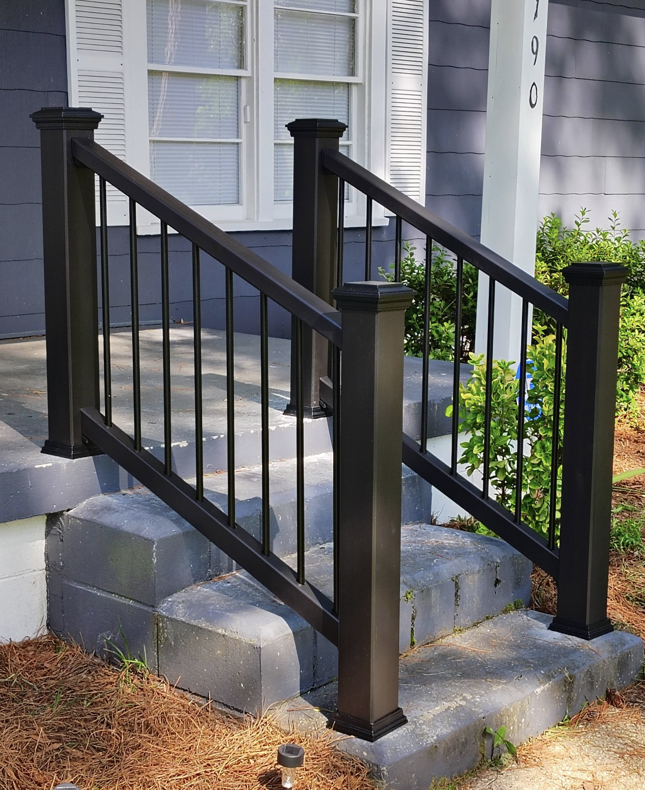 After renovation — black metal balcony railing with decorative posts alongside gray stone steps