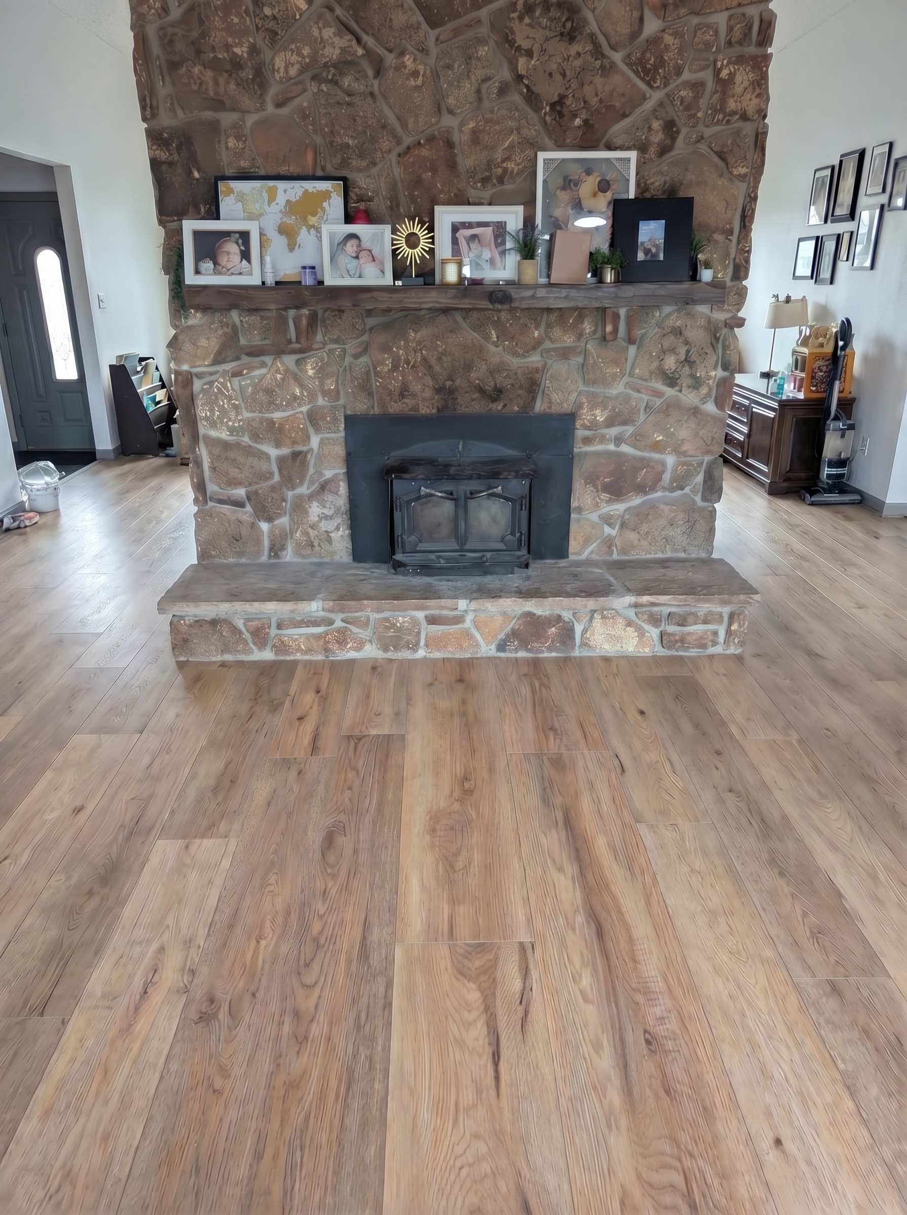 Prominent stone fireplace with a wooden mantel adorned with framed photos and decor