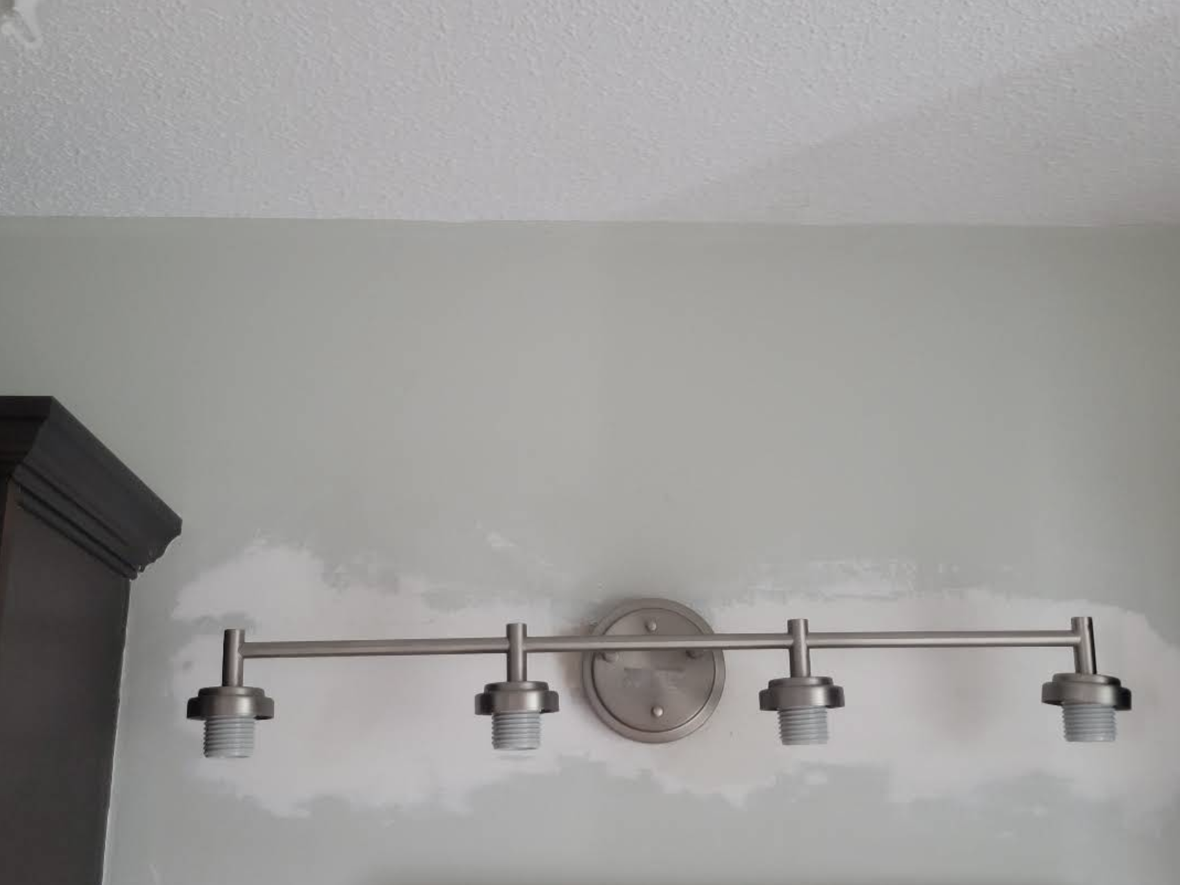Modern four-socket wall-mounted light fixture installed against a freshly painted wall