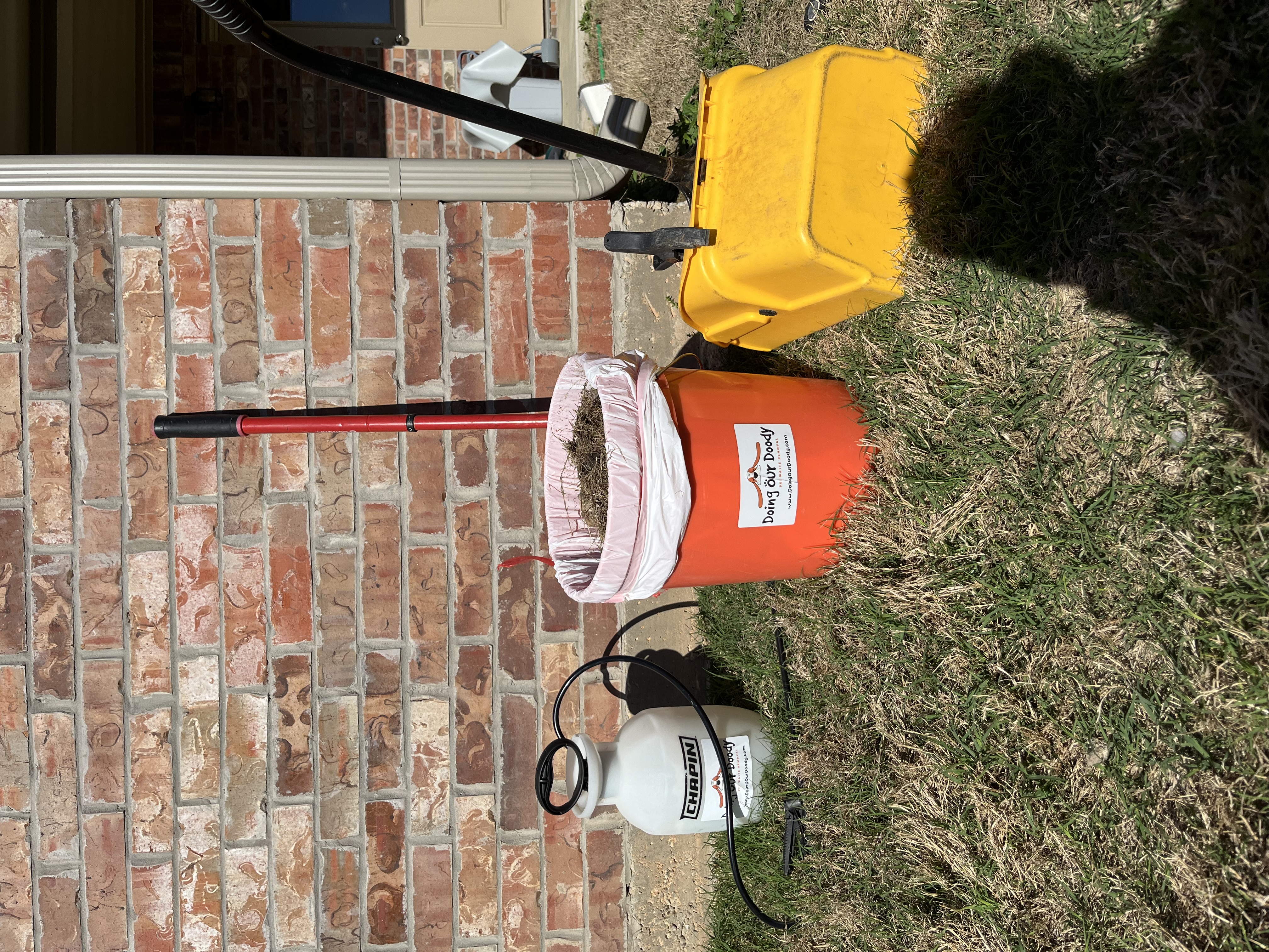 Doing Our Doody deodorizing and cleanup equipment including sprayer, rake, and branded bucket
