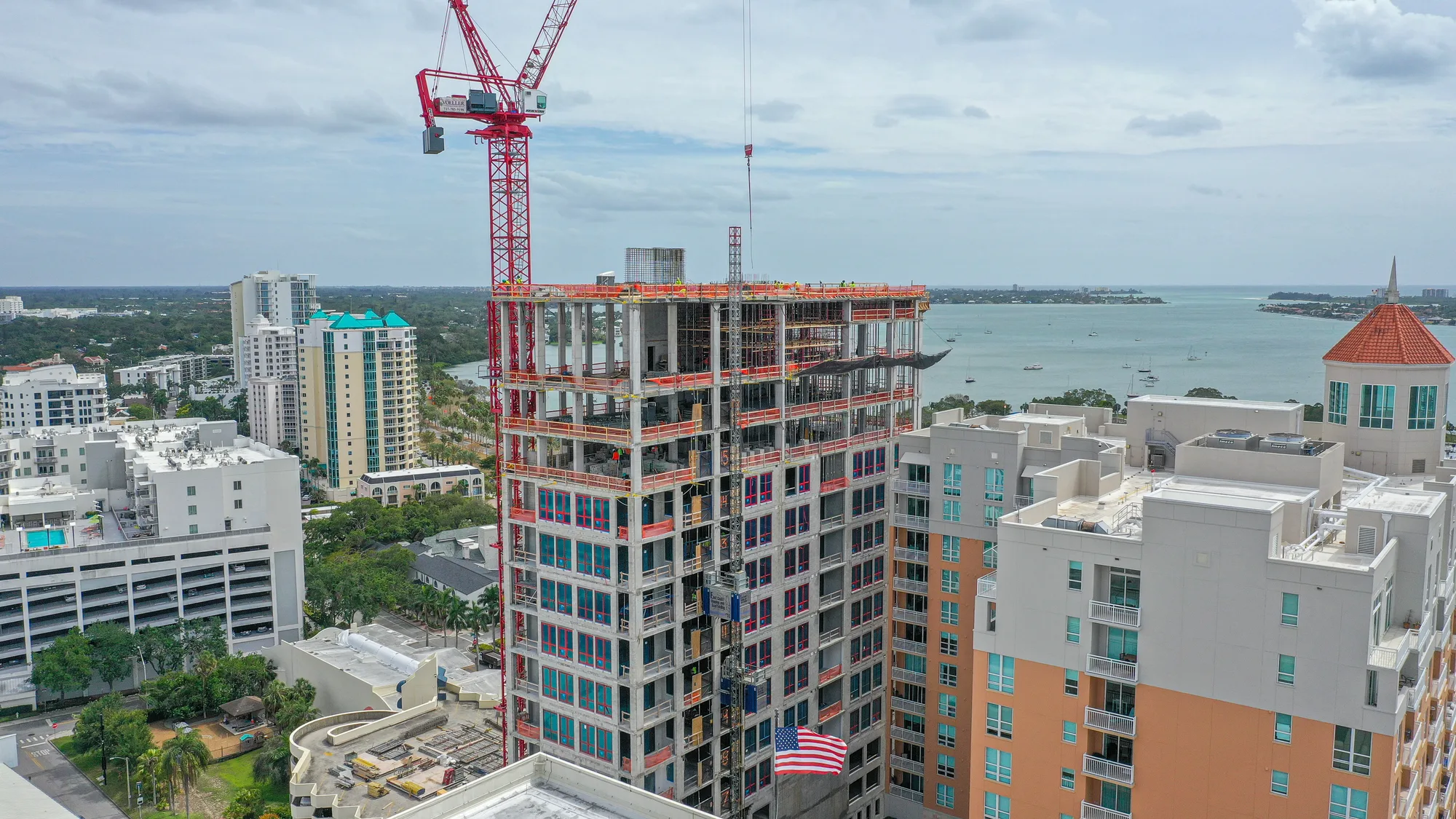 The DeMarcay under construction, its concrete frame rising above neighbouring buildings with Sarasota Bay behind.
