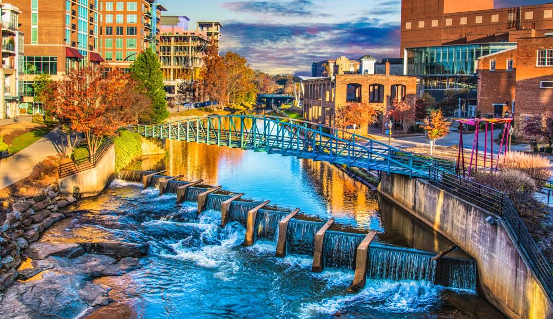 Cityscape with stream and pedestrian bridge in Greenville, SC