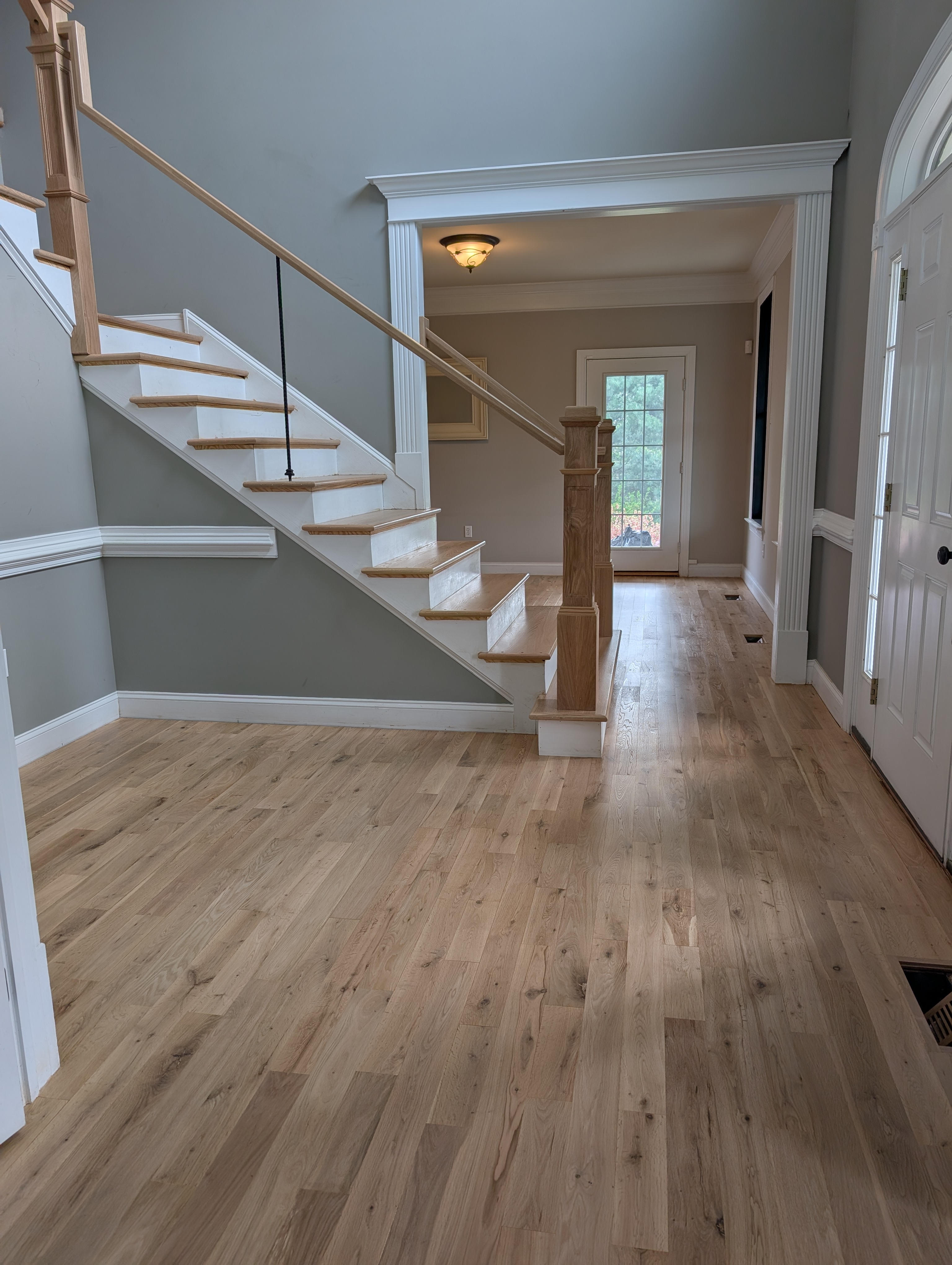 Custom hardwood staircase with matching railing in a bright entryway