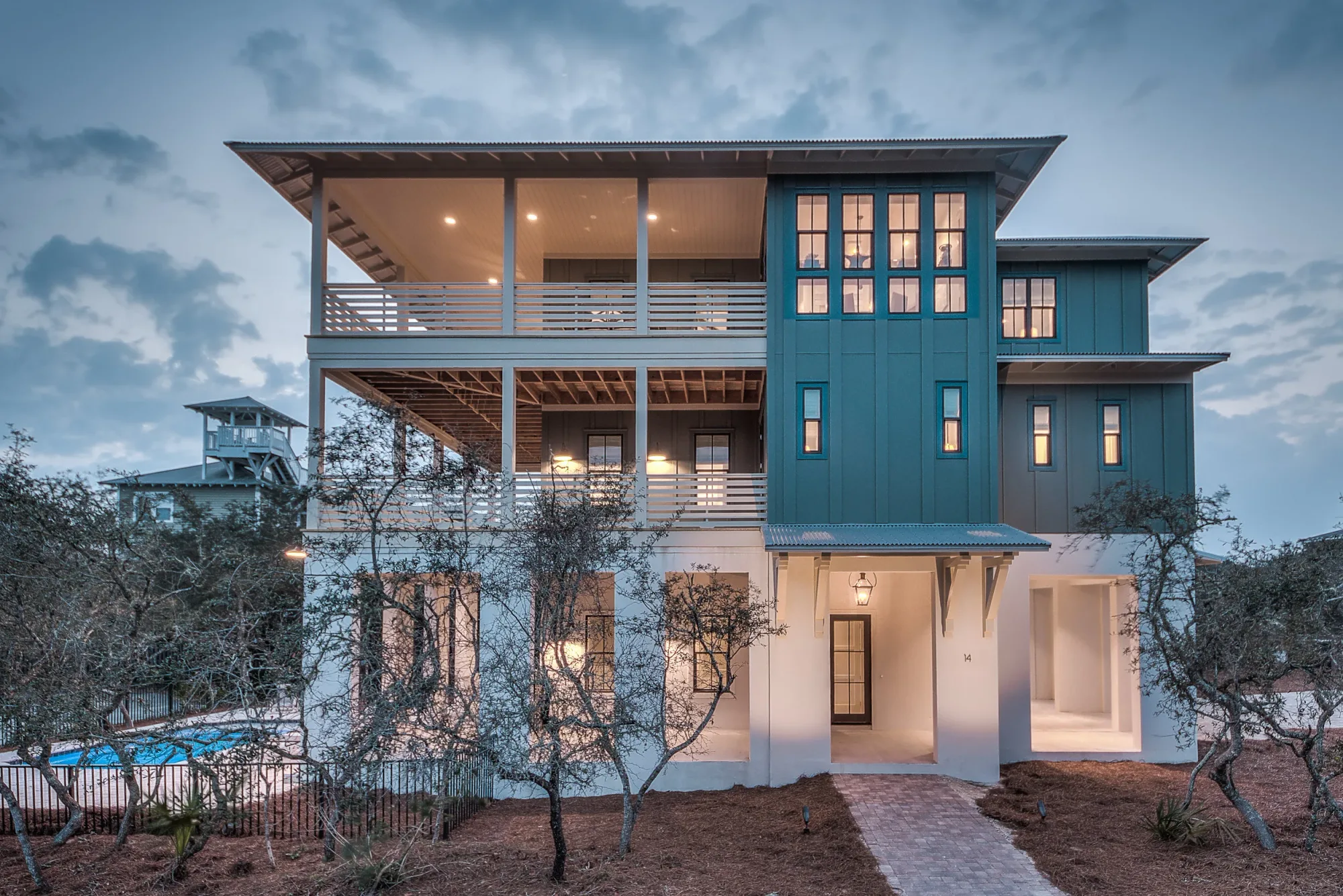 A completed JAT Specialties custom home at dusk, with deep covered porches and a standing-seam metal roof.