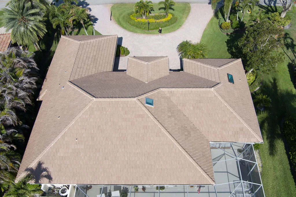 Aerial drone view of a multi-angled brown composite tile roof on a Florida home surrounded by palm trees