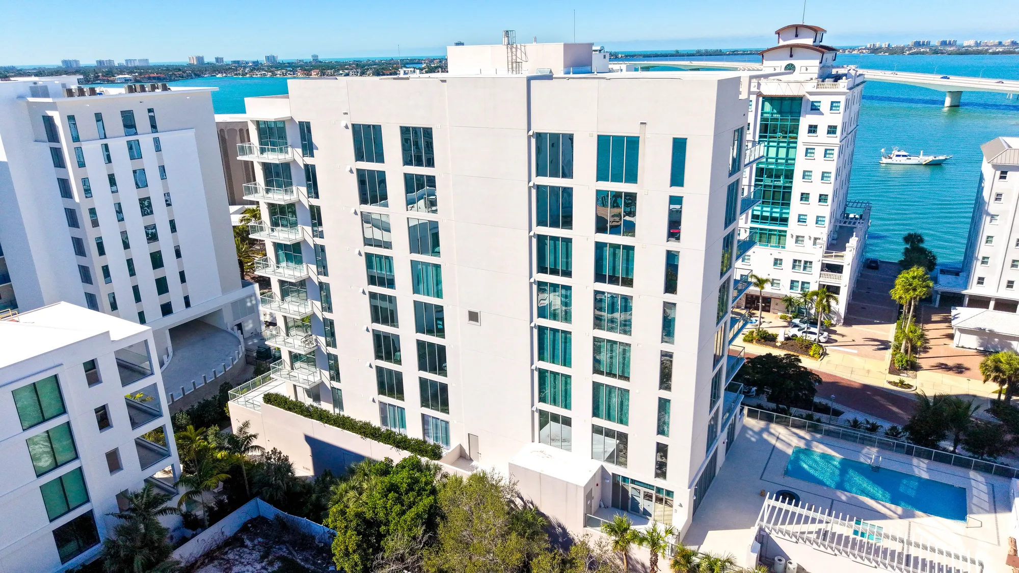 Aerial of The Epoch, a glass-and-white residential tower, against a clear blue sky.