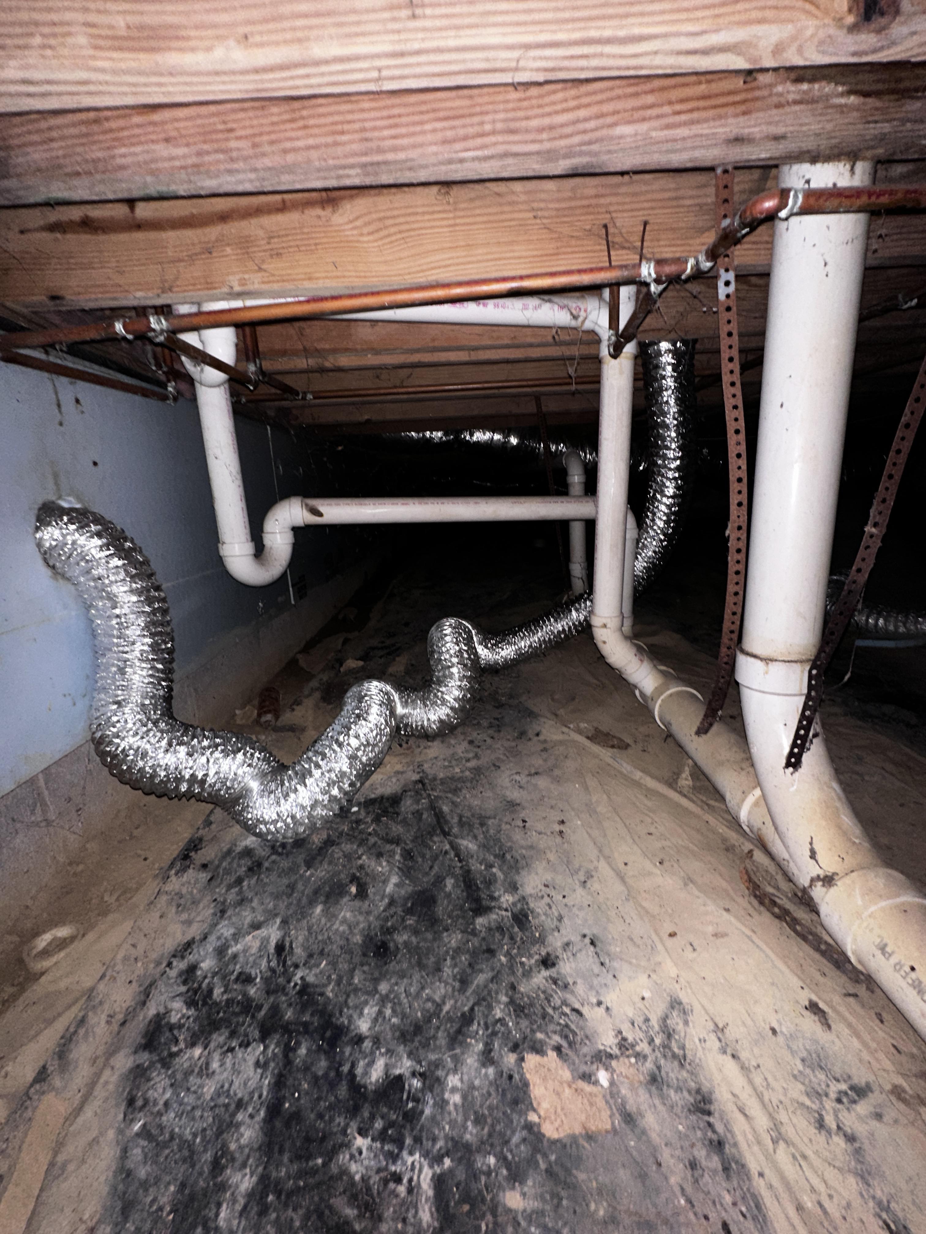 View of crawl space beneath a house showing pipes and a flexible duct