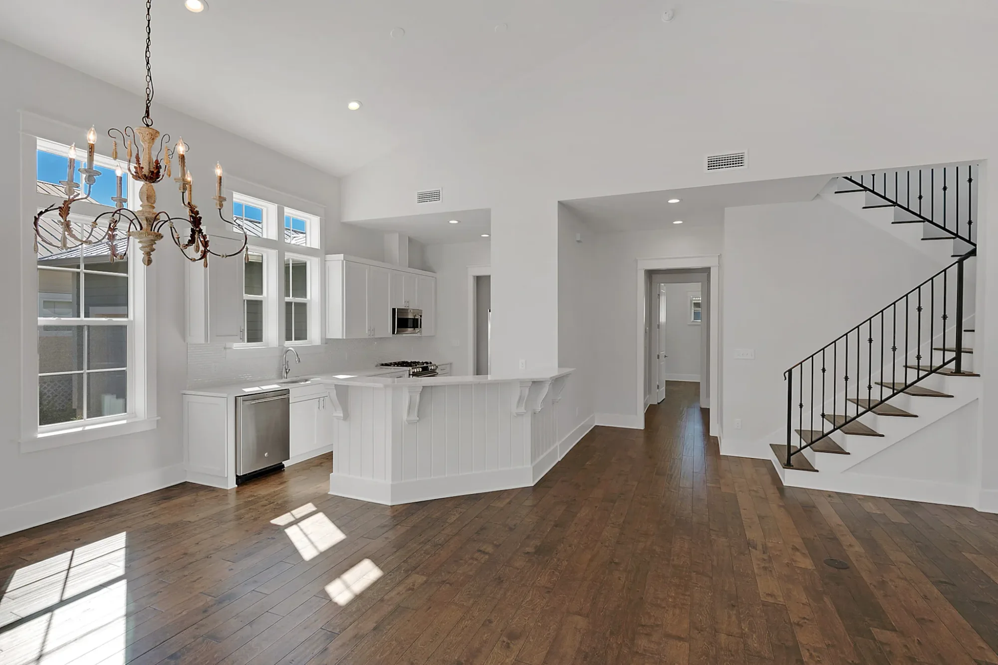 A finished kitchen and great room with white shaker cabinetry and wide-plank hardwood floors.