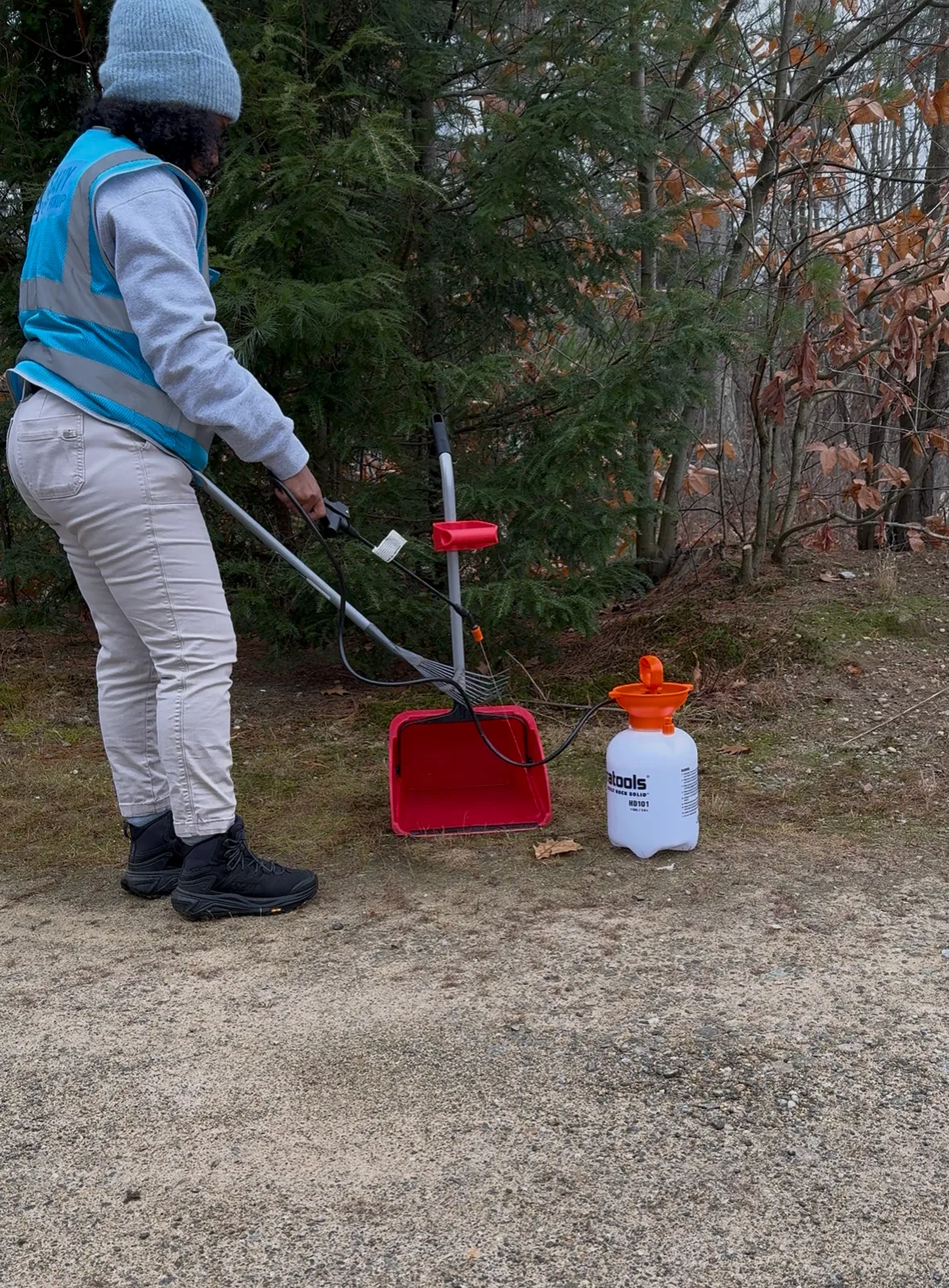 Savy Poop Pickup technician spraying the red scoop and rake with pet safe, kennel grade disinfectant between properties