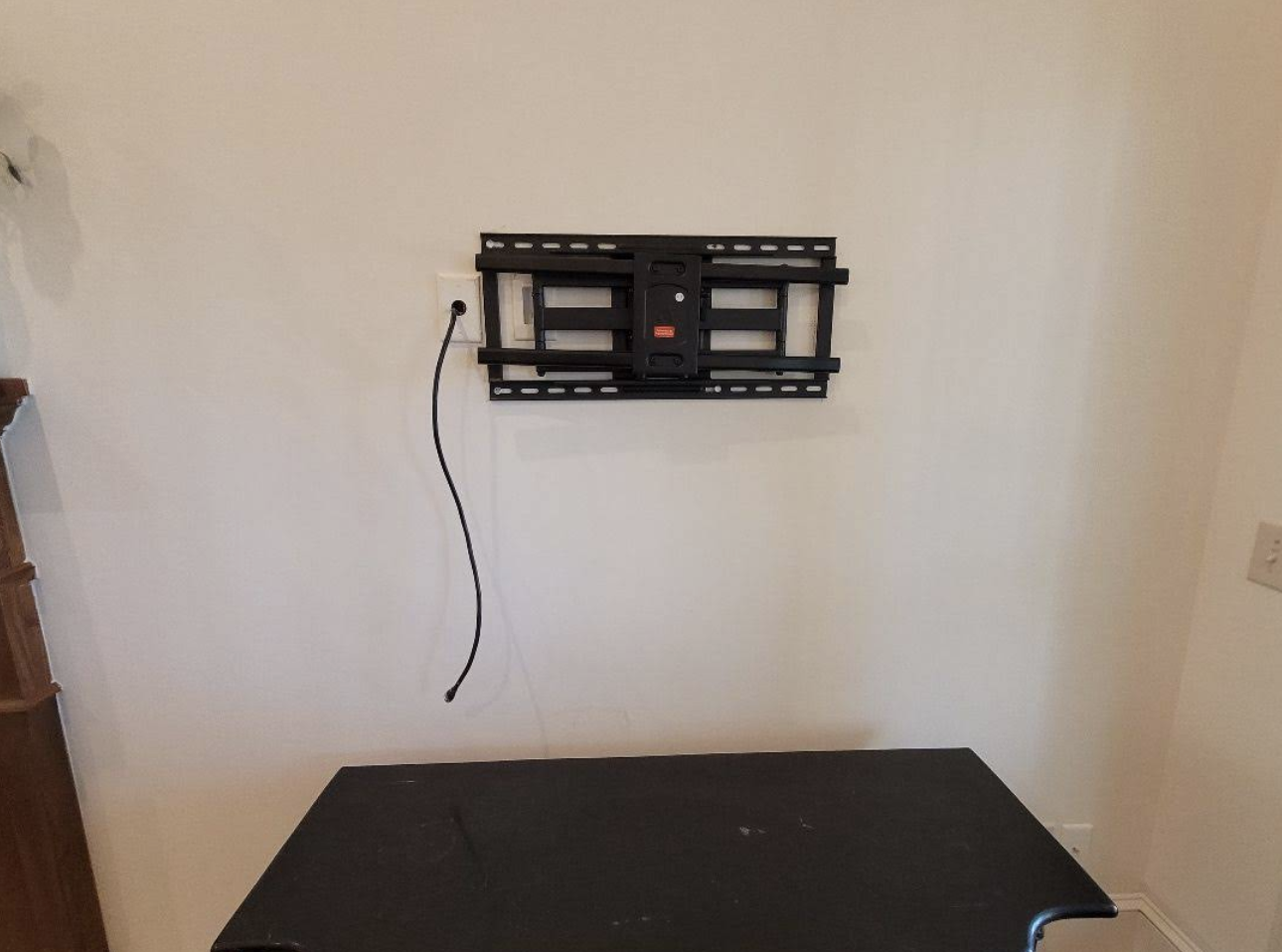Black wall-mounted TV bracket freshly installed on a white wall