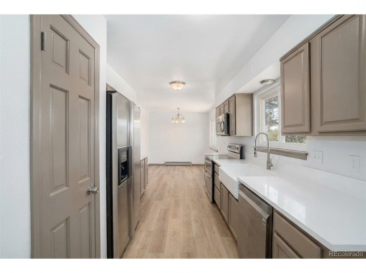 Contemporary kitchen with stainless steel appliances, light brown cabinetry, and white countertop