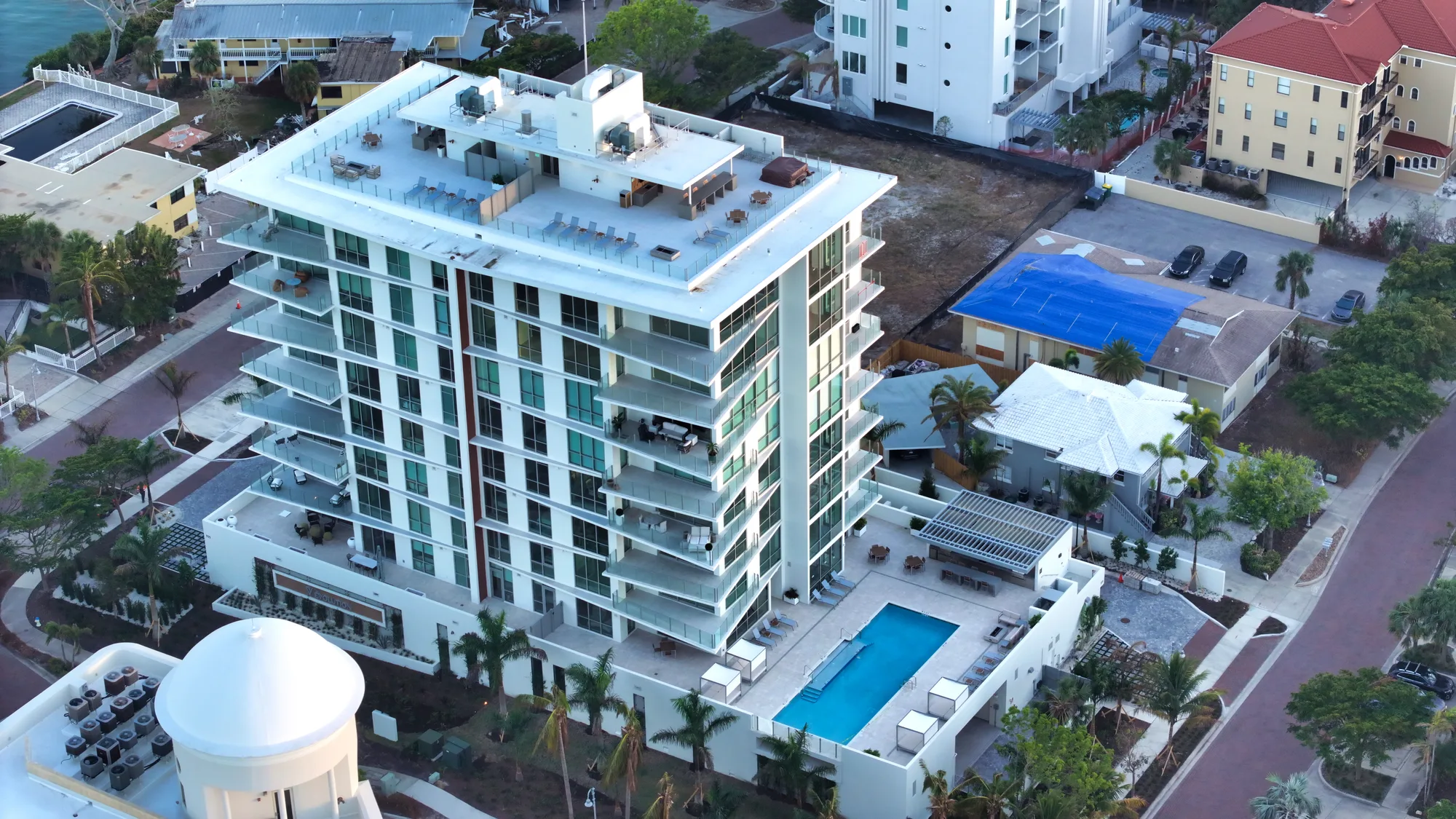 Aerial of The Evolution, a white multi-storey residential building with a pool, in a Sarasota neighbourhood.