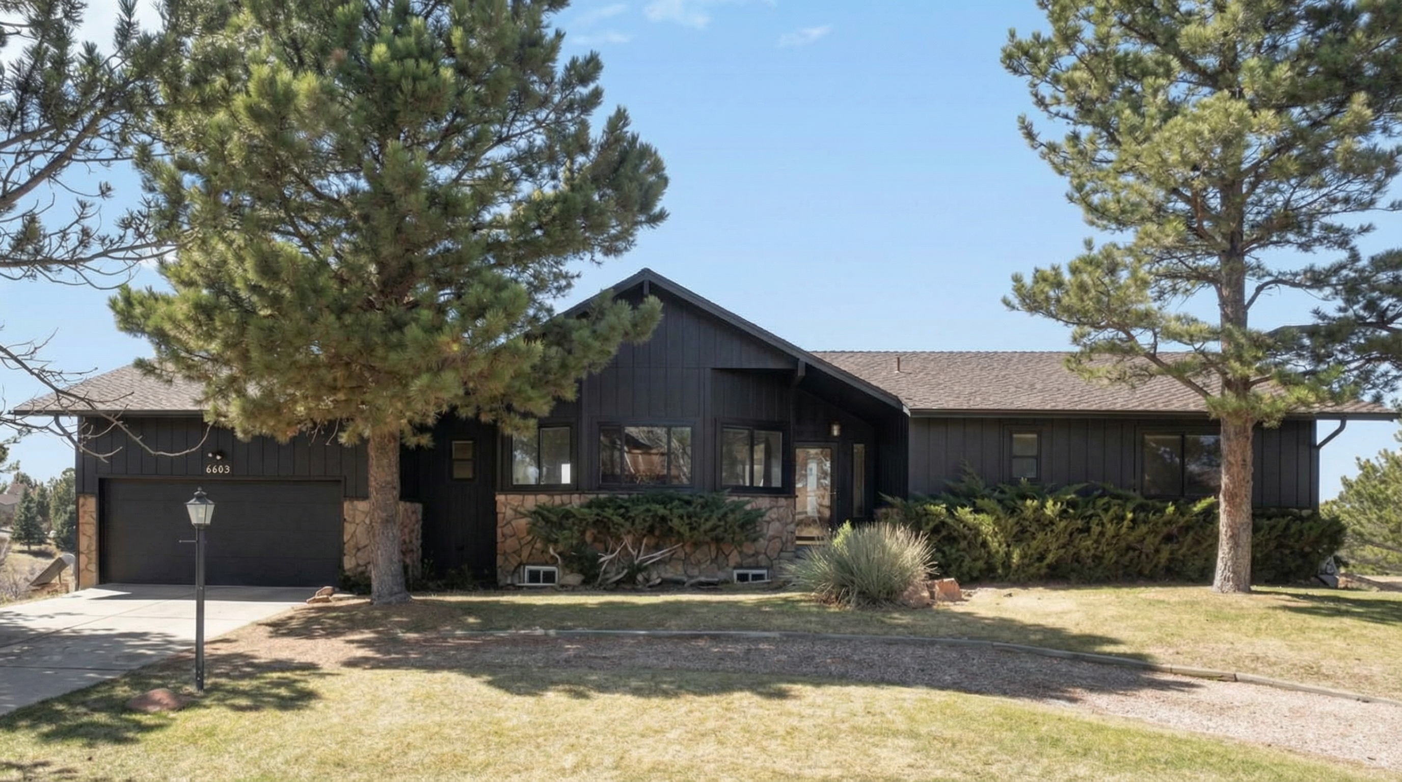 Stylish single-story home with black exterior and stone accents