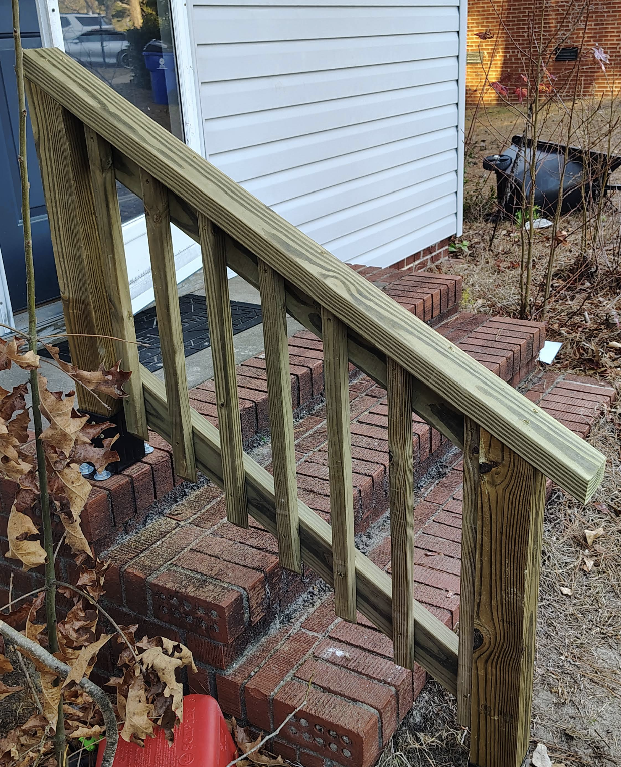 Wooden railing and trim work on brick steps leading up to a front entry