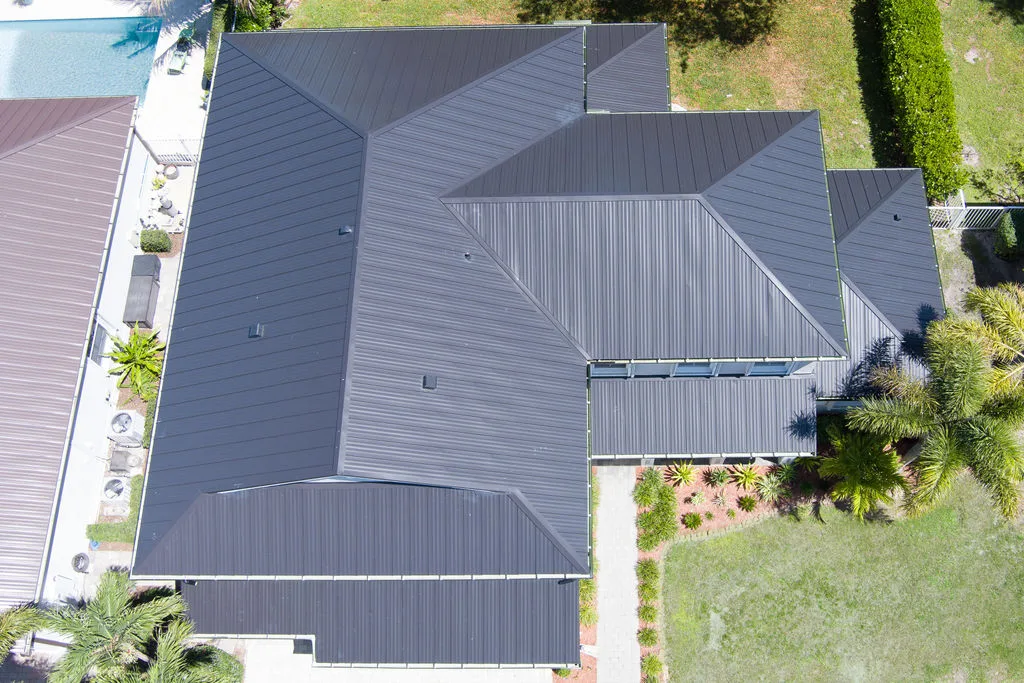 Aerial view of a contemporary home on the Treasure Coast with a sleek black metal roof and pool