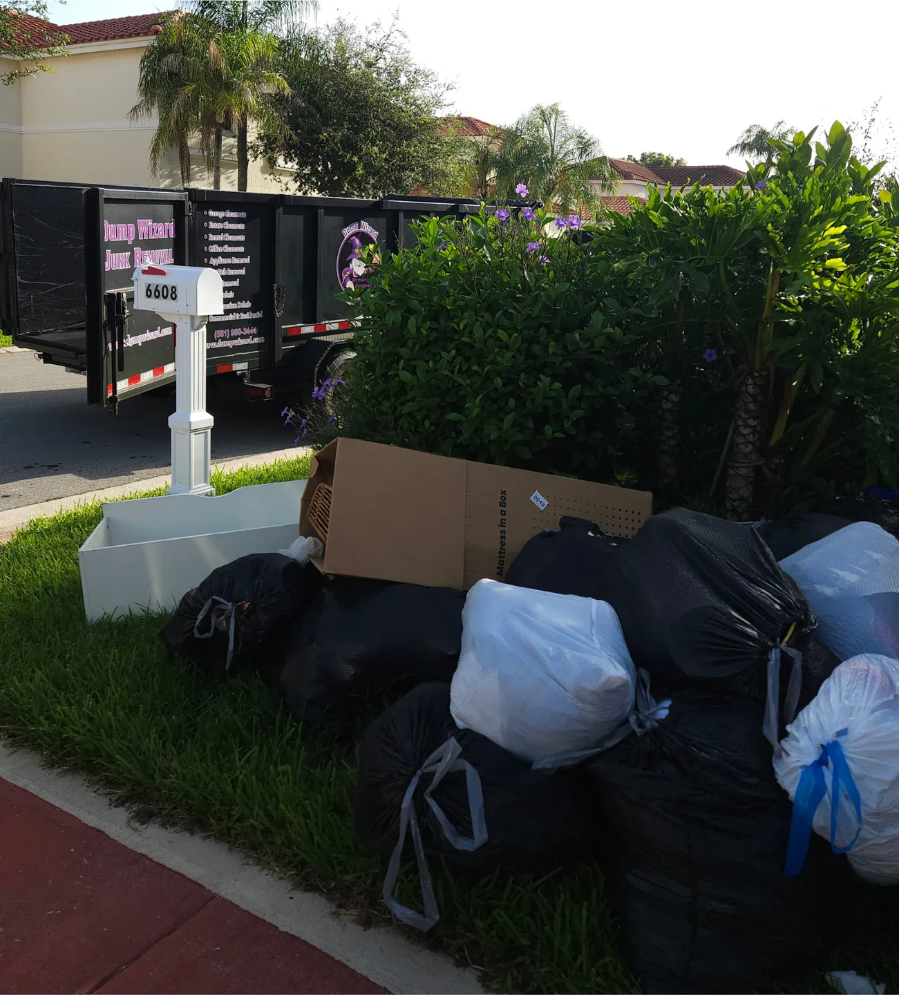 Bagged junk and boxes staged at the curb as the Dump Wizard trailer arrives to load