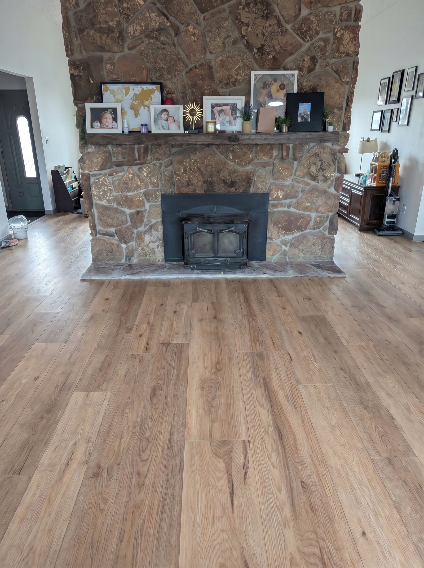 Well-lit living room with a large stone fireplace adorned with family photos and decorative items
