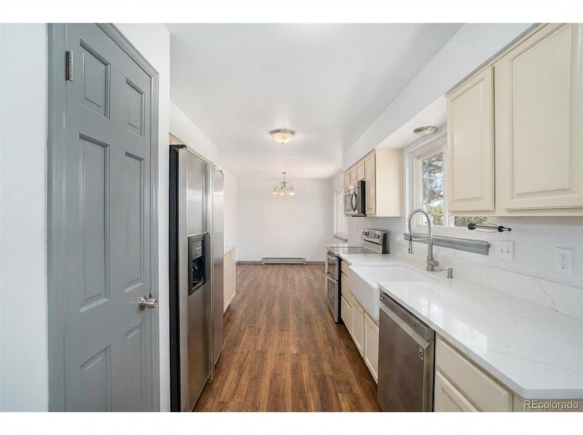 Spacious kitchen with white cabinetry, stainless steel appliances, and hardwood flooring