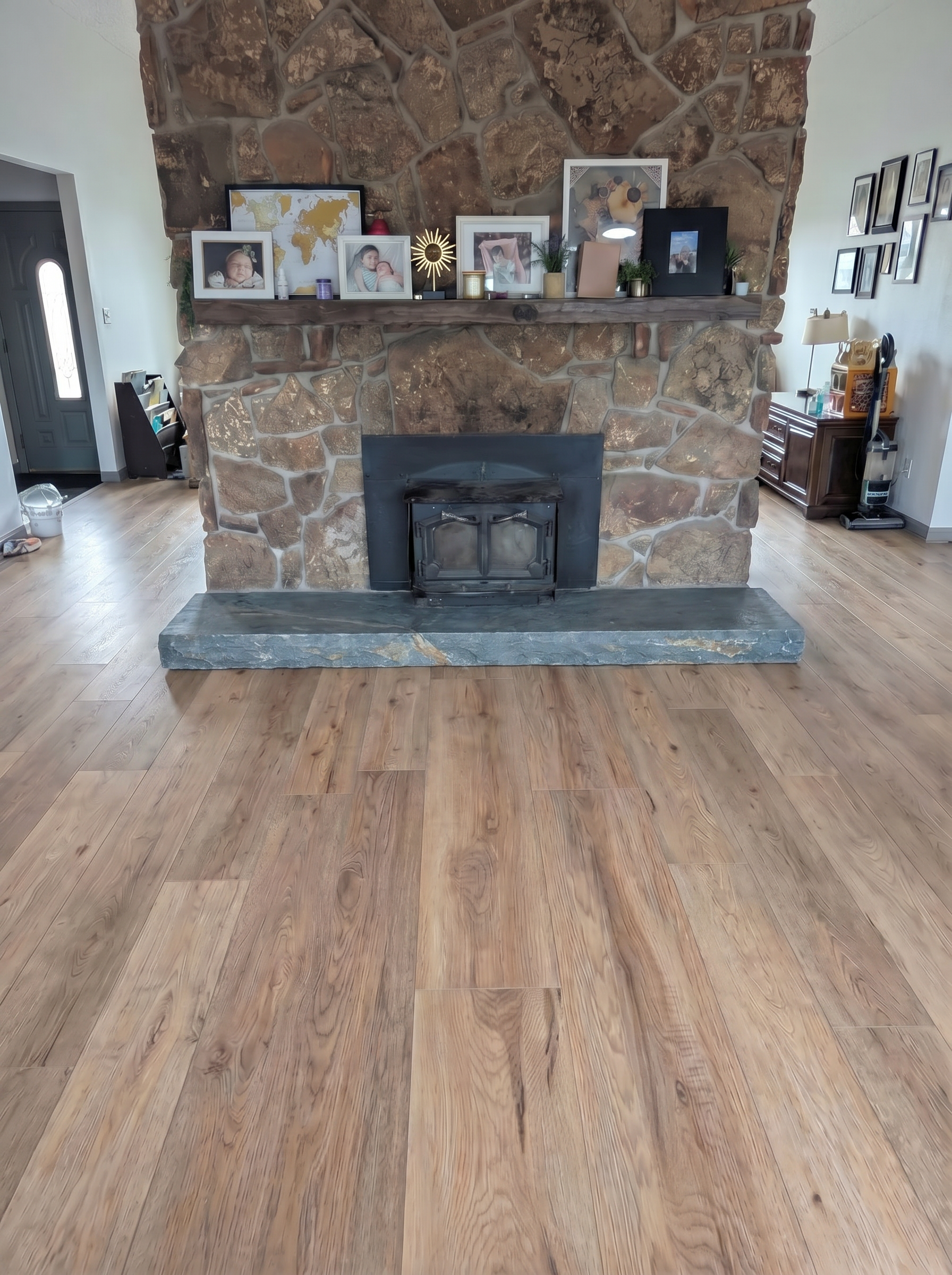 Stone fireplace with a black stove insert, decorated with framed photos and a wall-mounted map
