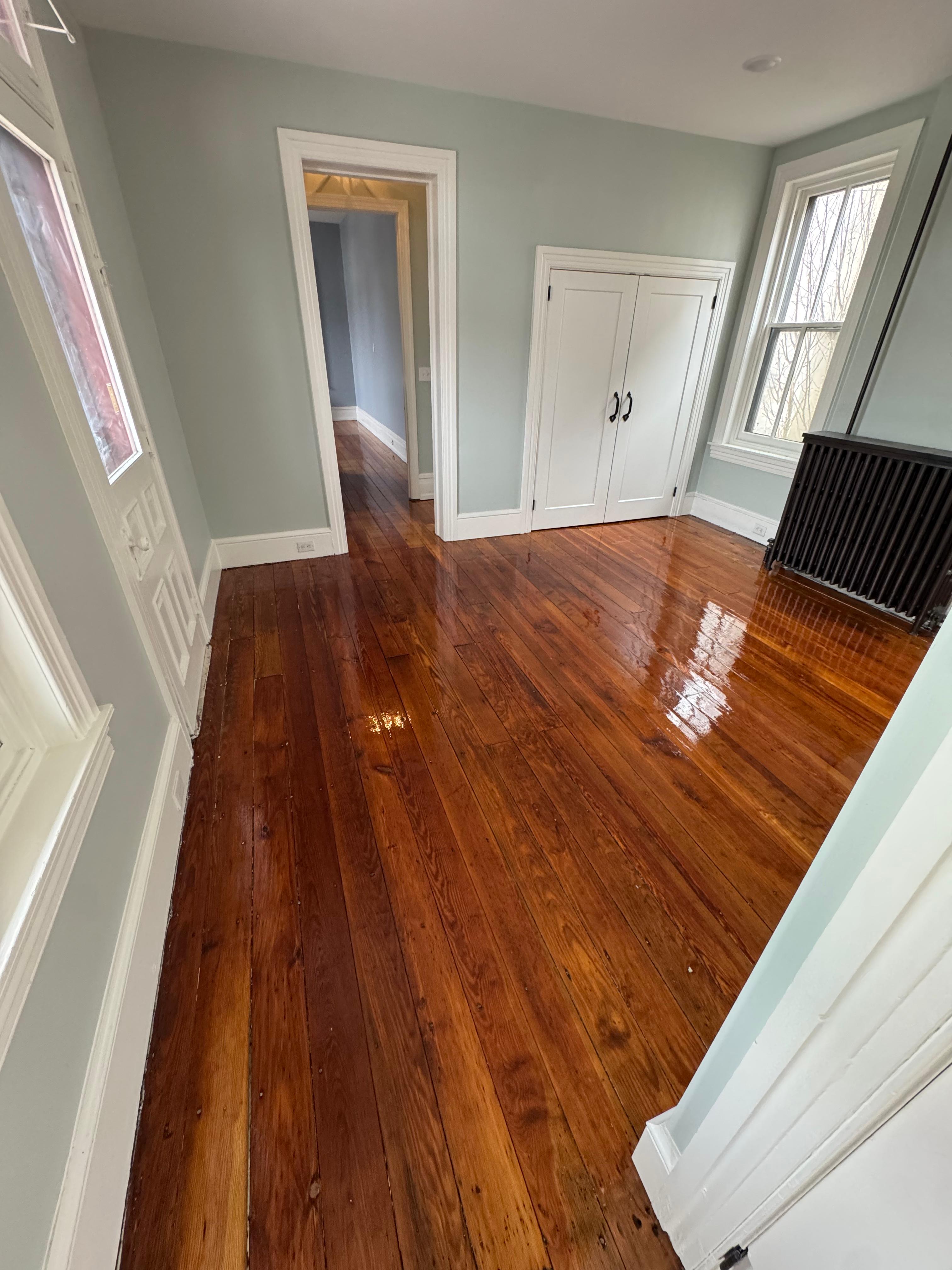 Spacious room with gleaming polished hardwood floors and light blue walls