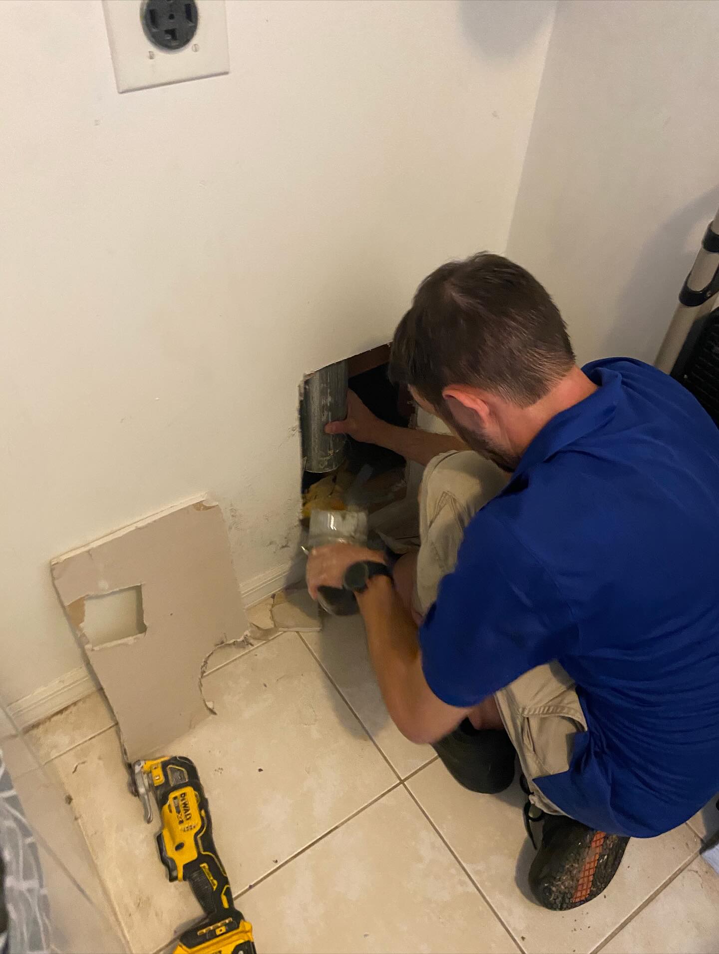 Technician repairing a wall opening during a dryer vent repair job