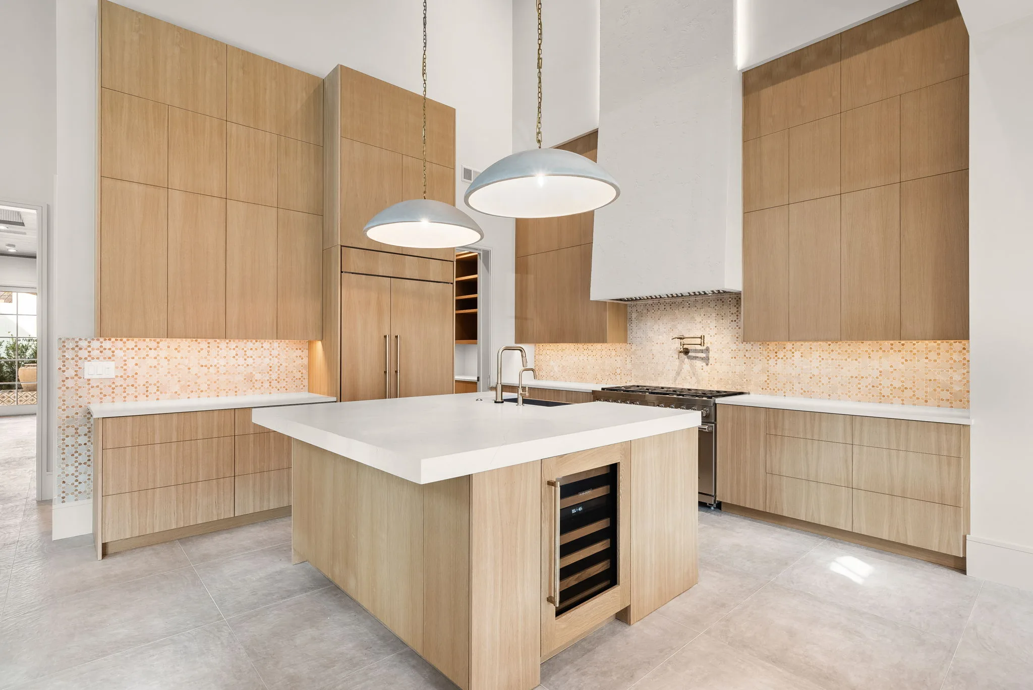 A kitchen with a white stone island, wood cabinetry and a wine cooler.