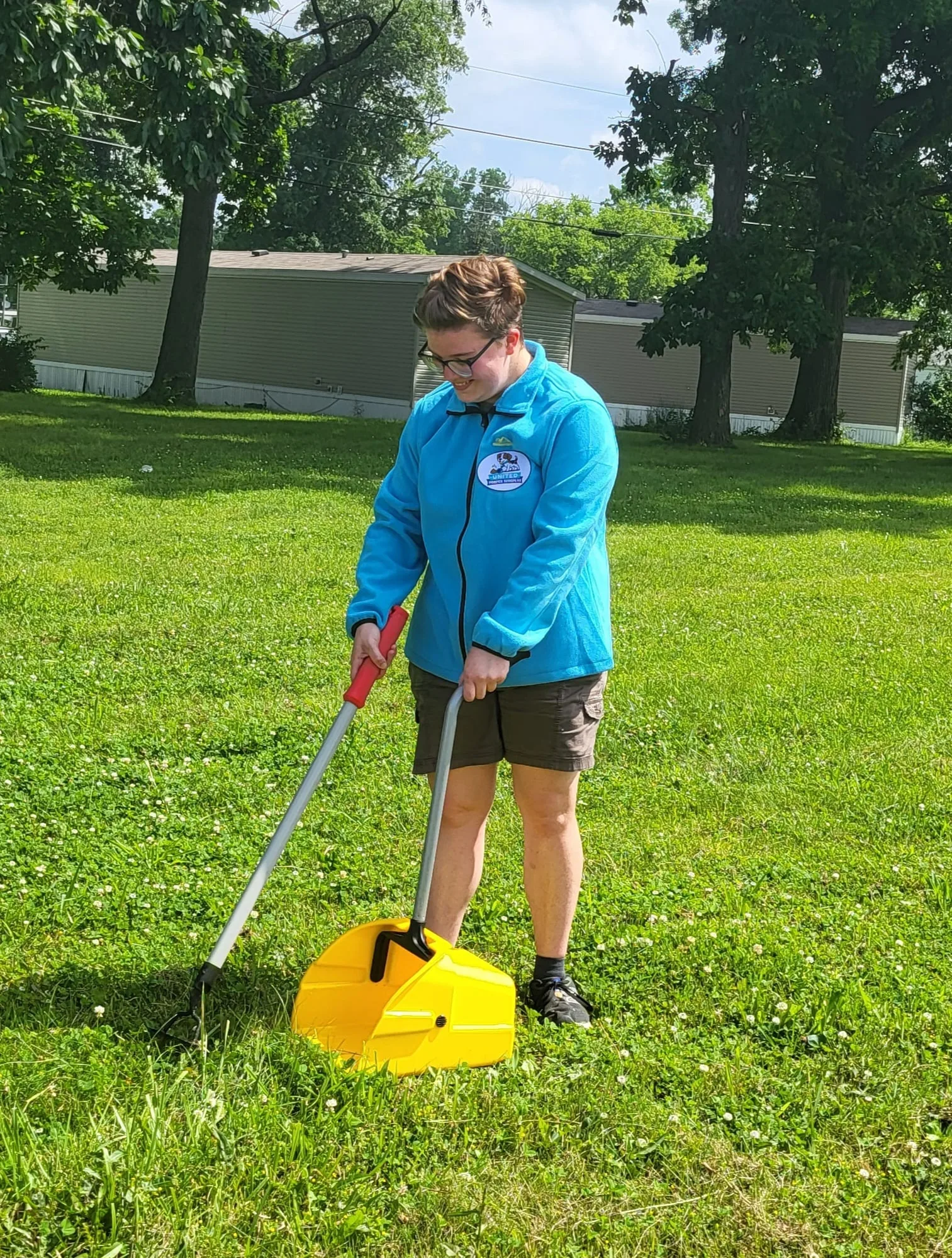 A United Pooper Scoopers team member scooping pet waste in a Muncie yard