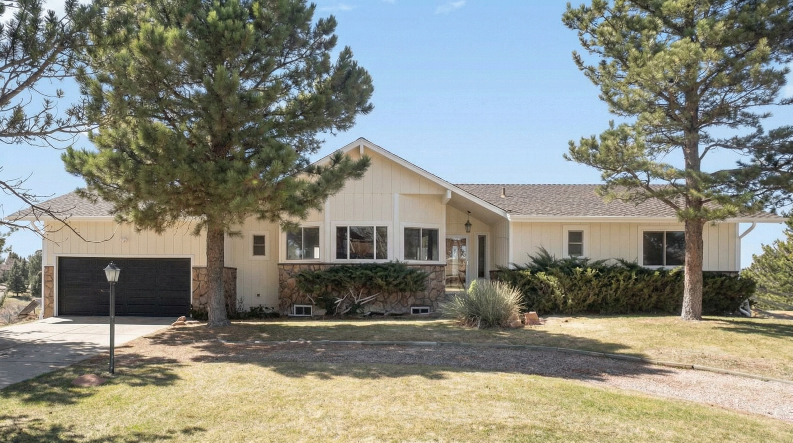 Single-story home with light-colored exterior and stone accents