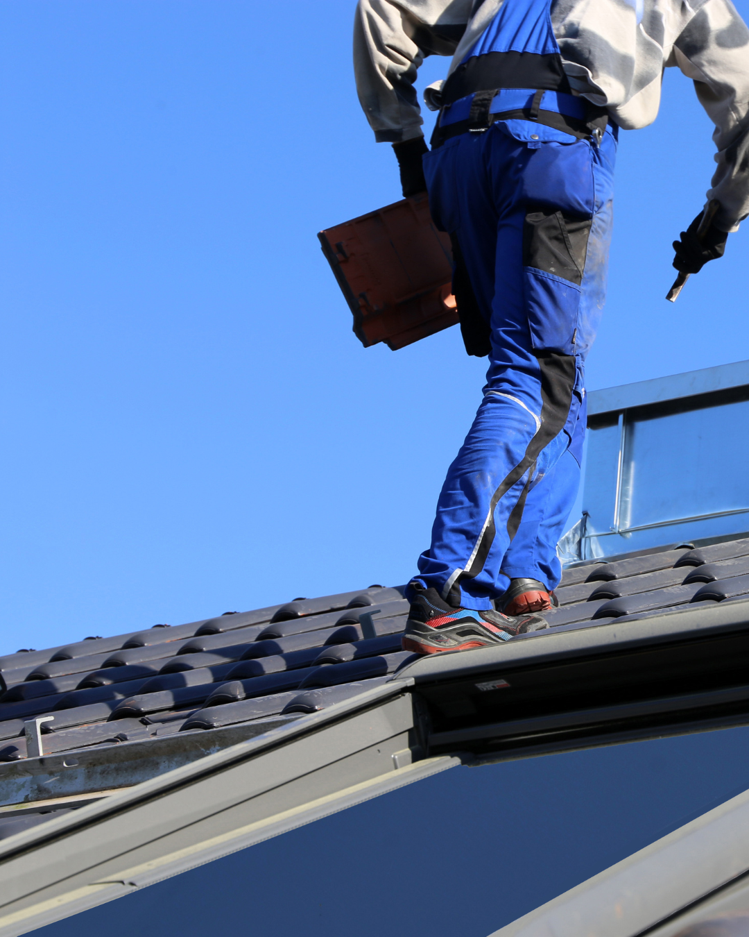 A roofing professional standing on a pitched residential roof performing a roof inspection on the Treasure Coast