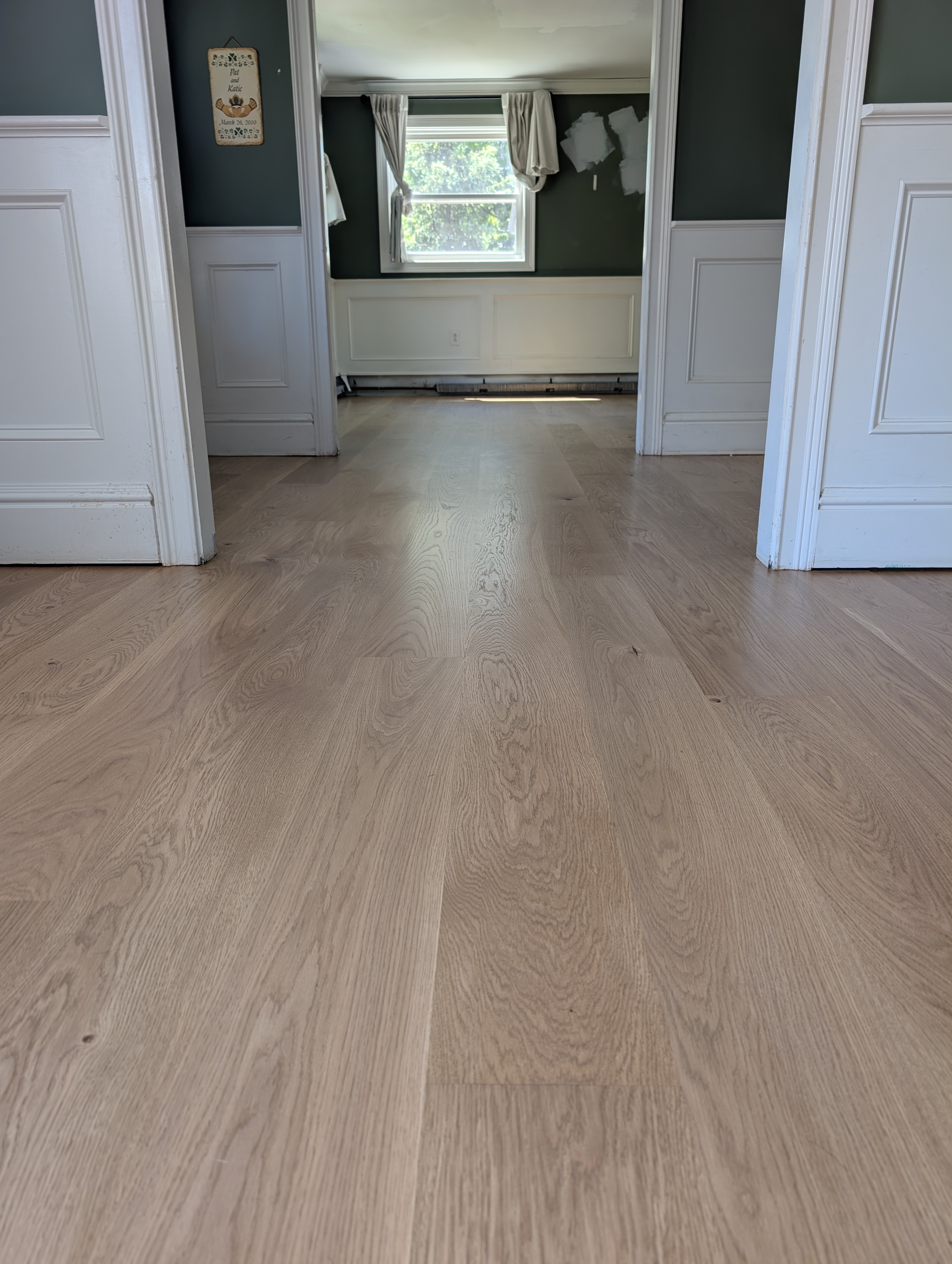 Freshly laid light-colored wooden flooring with doorways visible in background