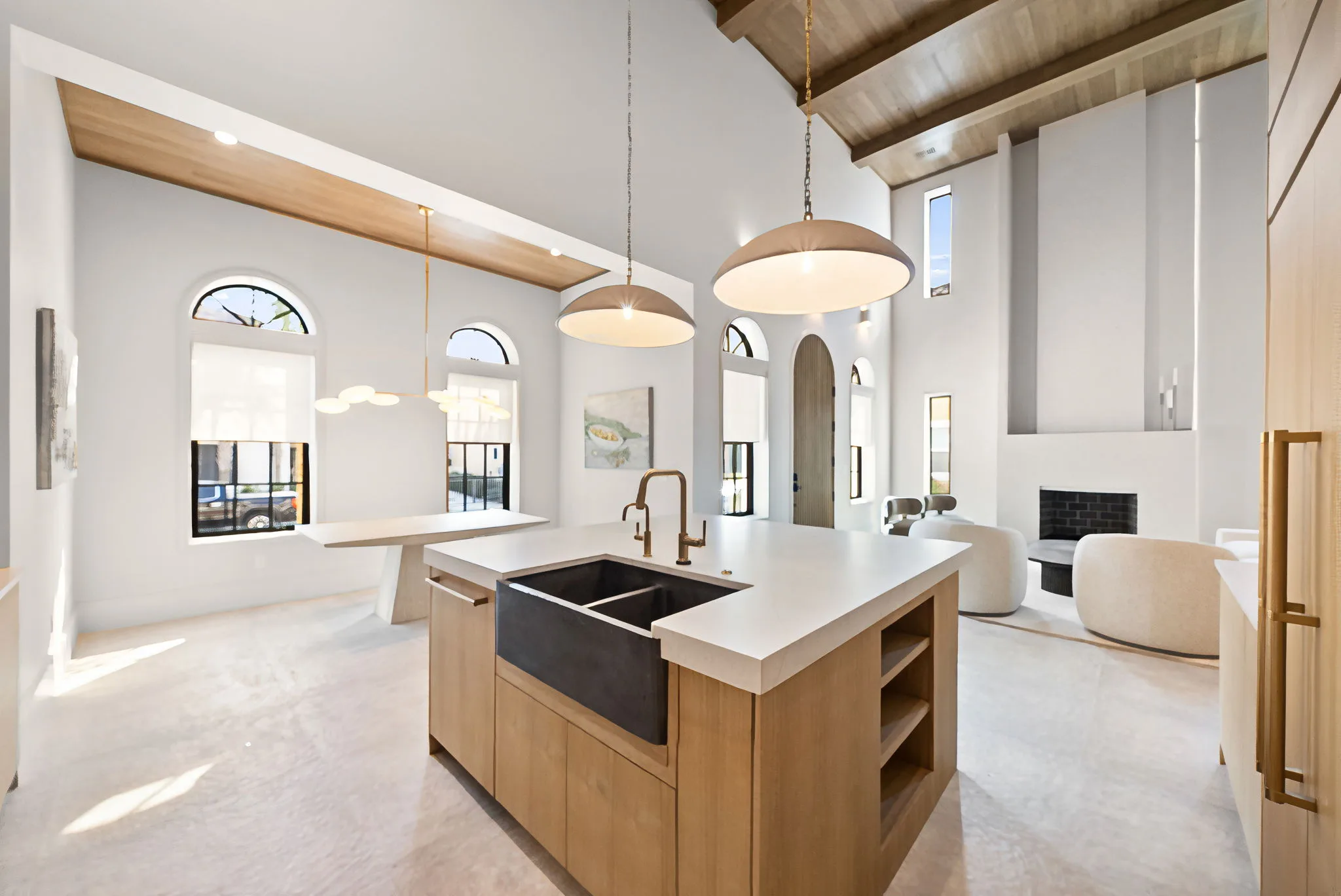 An open kitchen with a central island and wood cabinetry beneath a high vaulted ceiling with arched windows.