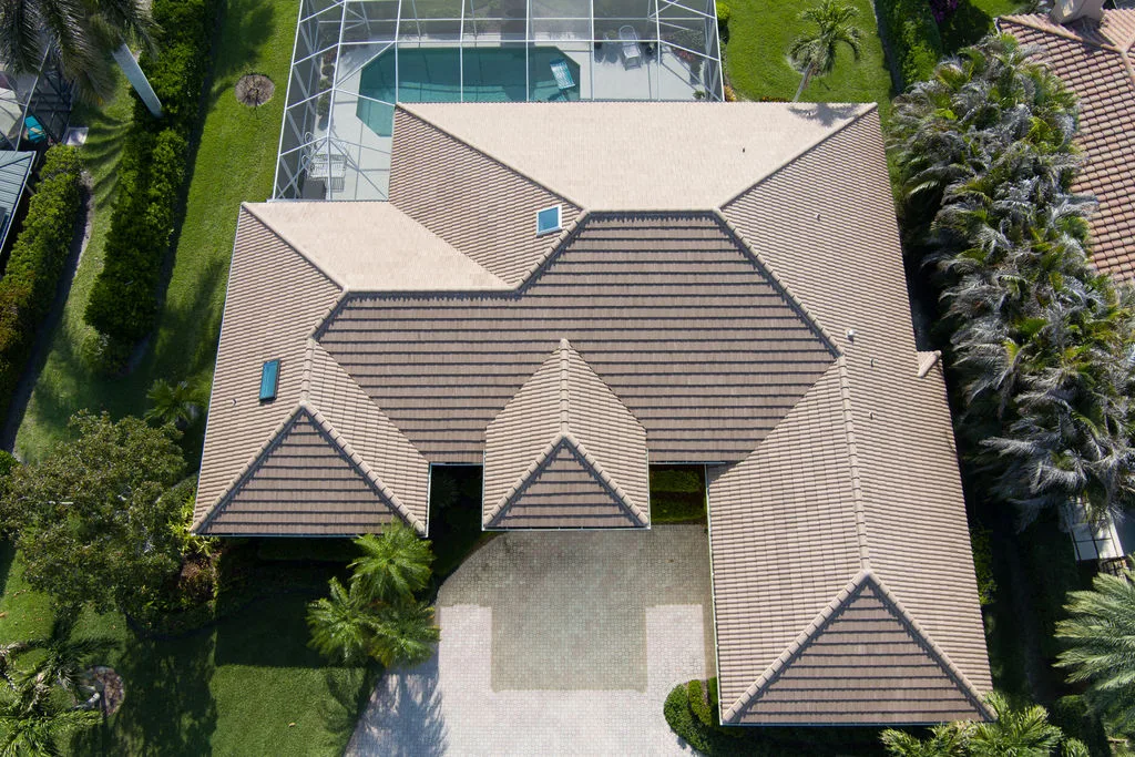 Aerial view of a contemporary home with a complex tiled roof design and pool