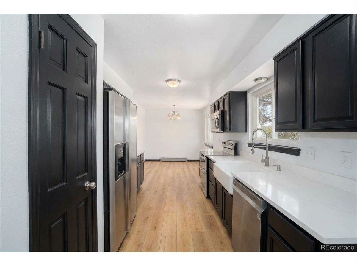 Modern kitchen interior with dark cabinetry, stainless steel appliances, and white countertop