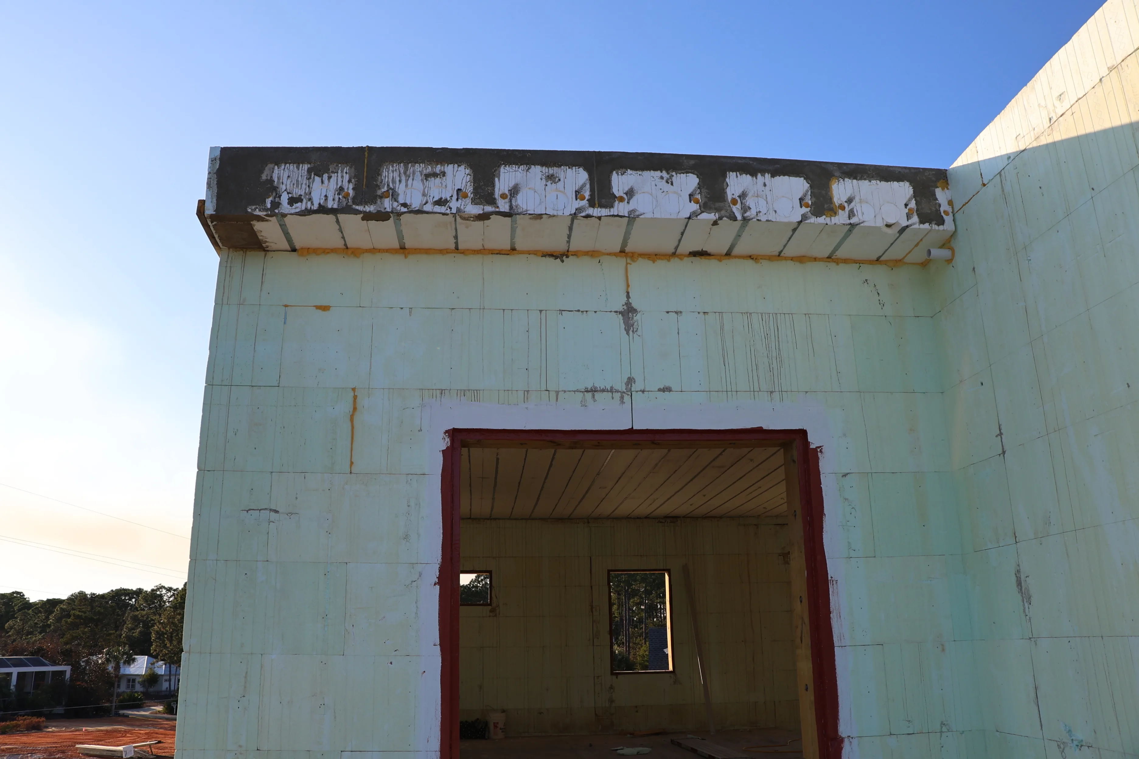 Close view of a pale-green insulated concrete form wall with a red-framed door opening.