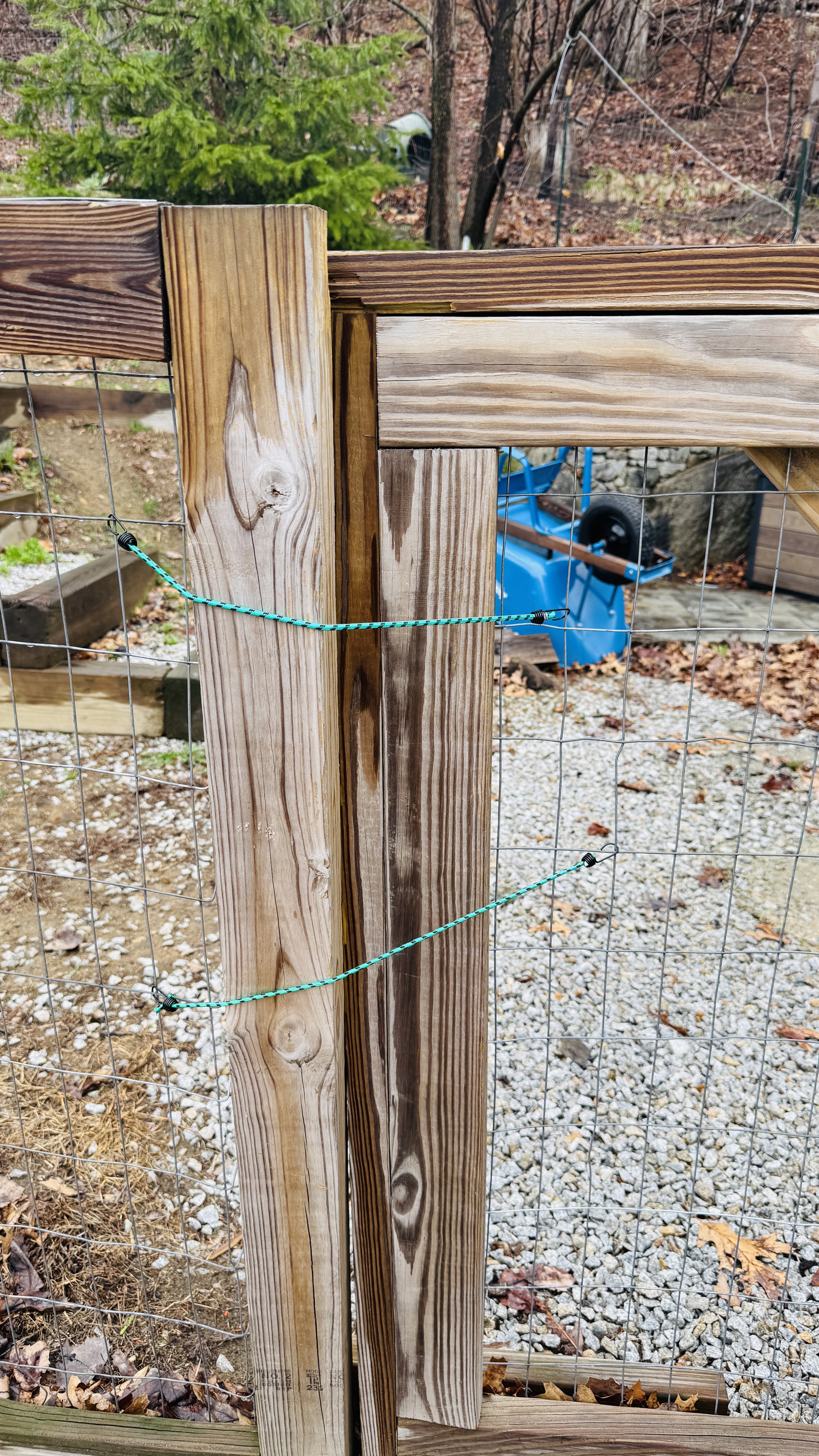 Close up of a wooden gate panel tied shut with green cord after a visit