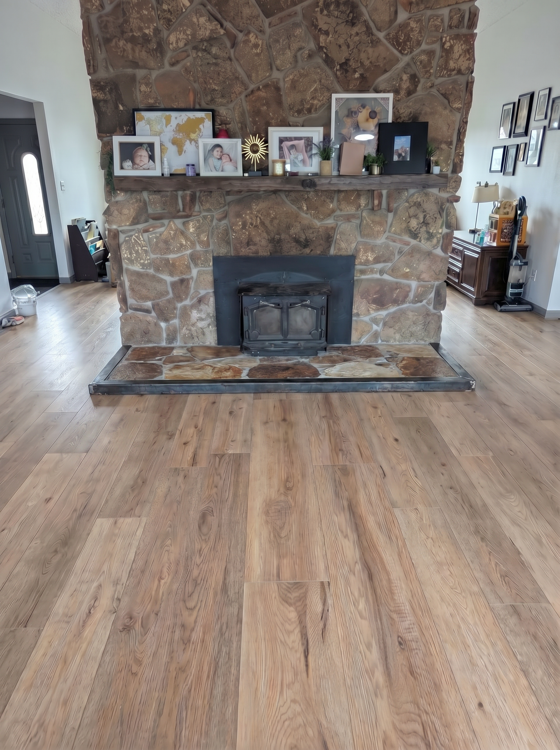 Living room with a large stone fireplace at the center adorned with framed photos and decorative items