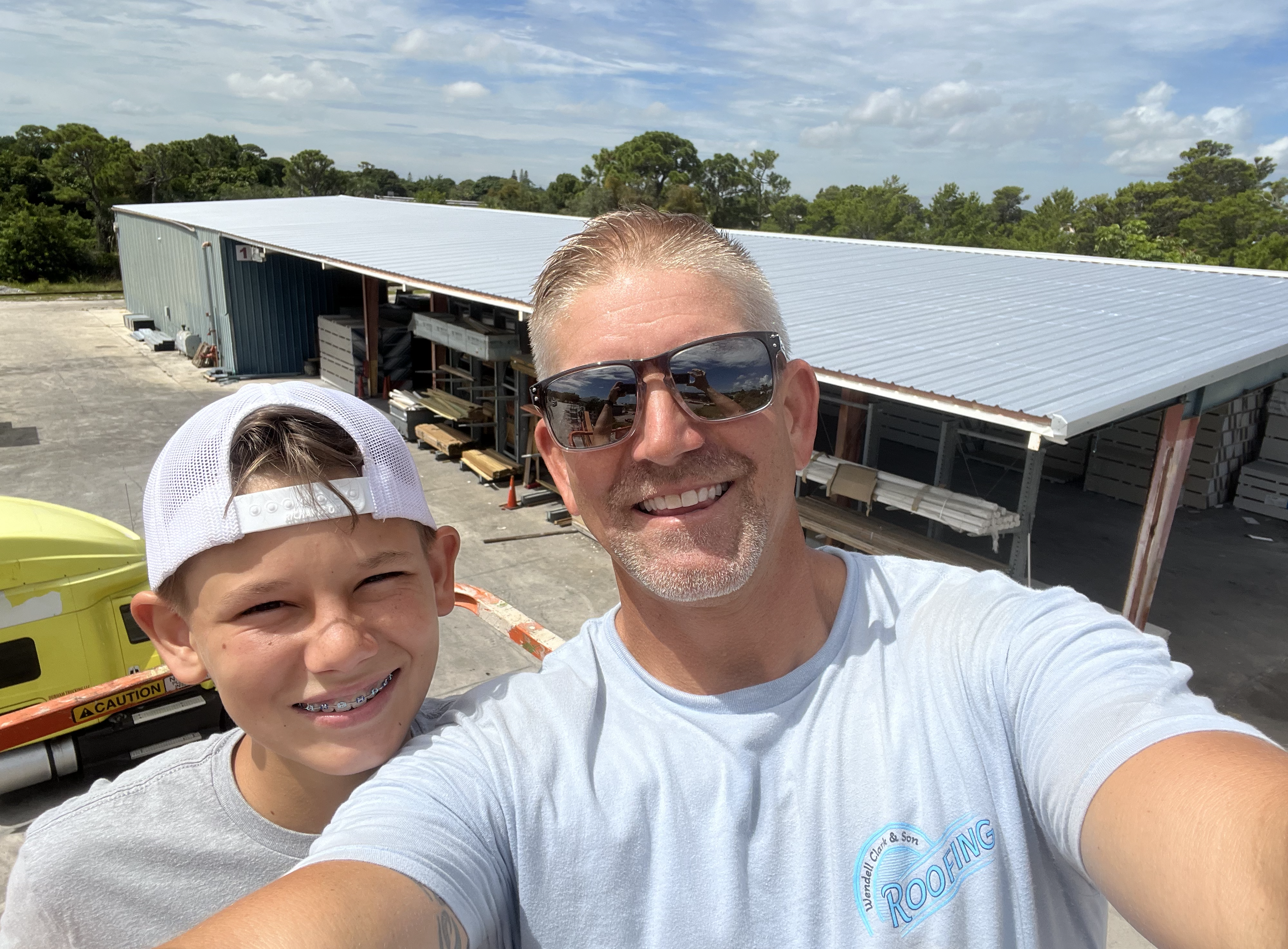 Crew at a commercial roofing job site with a blue metal roof in the background