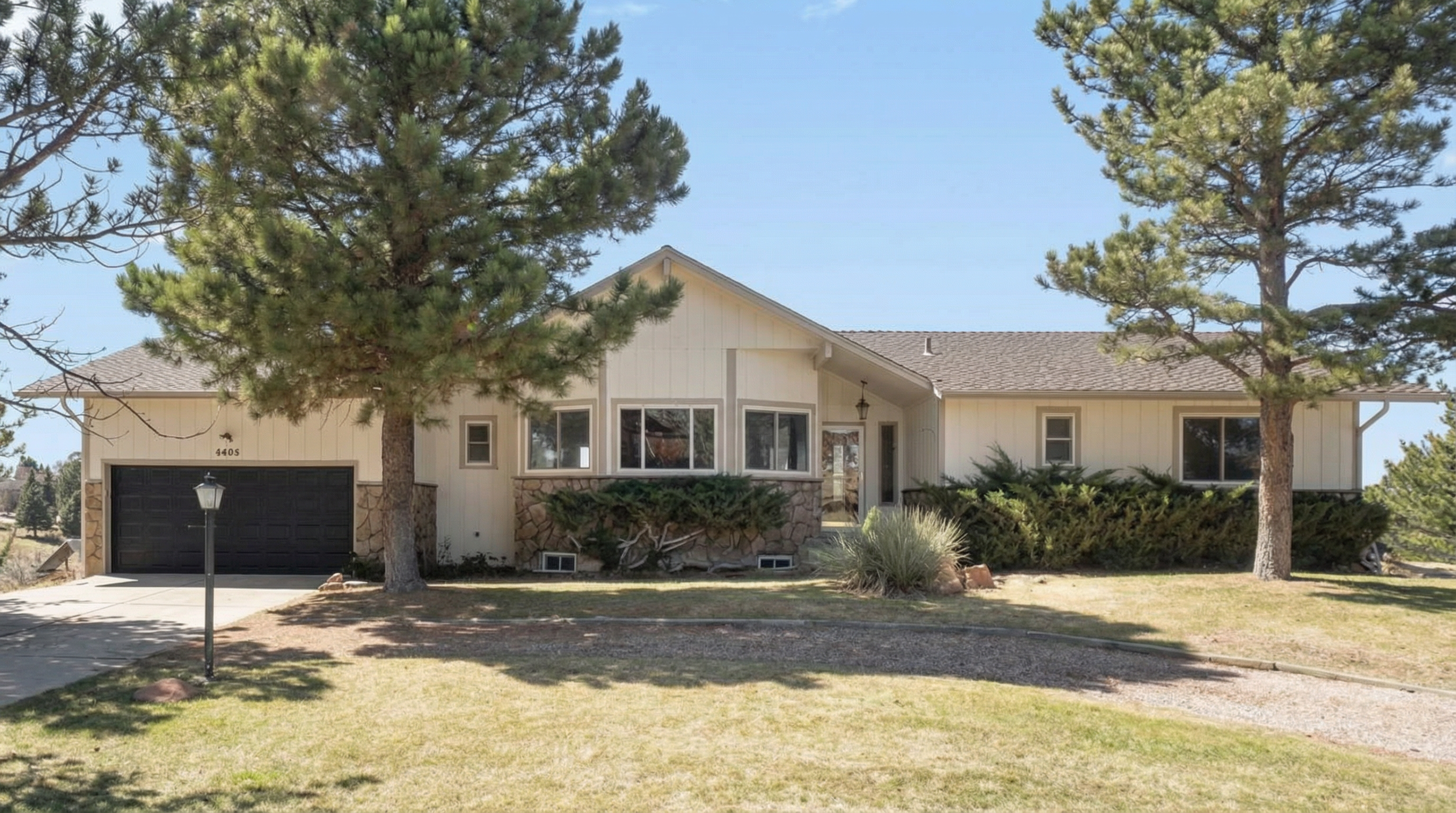 Single-story family home with light-colored exterior and stone foundation
