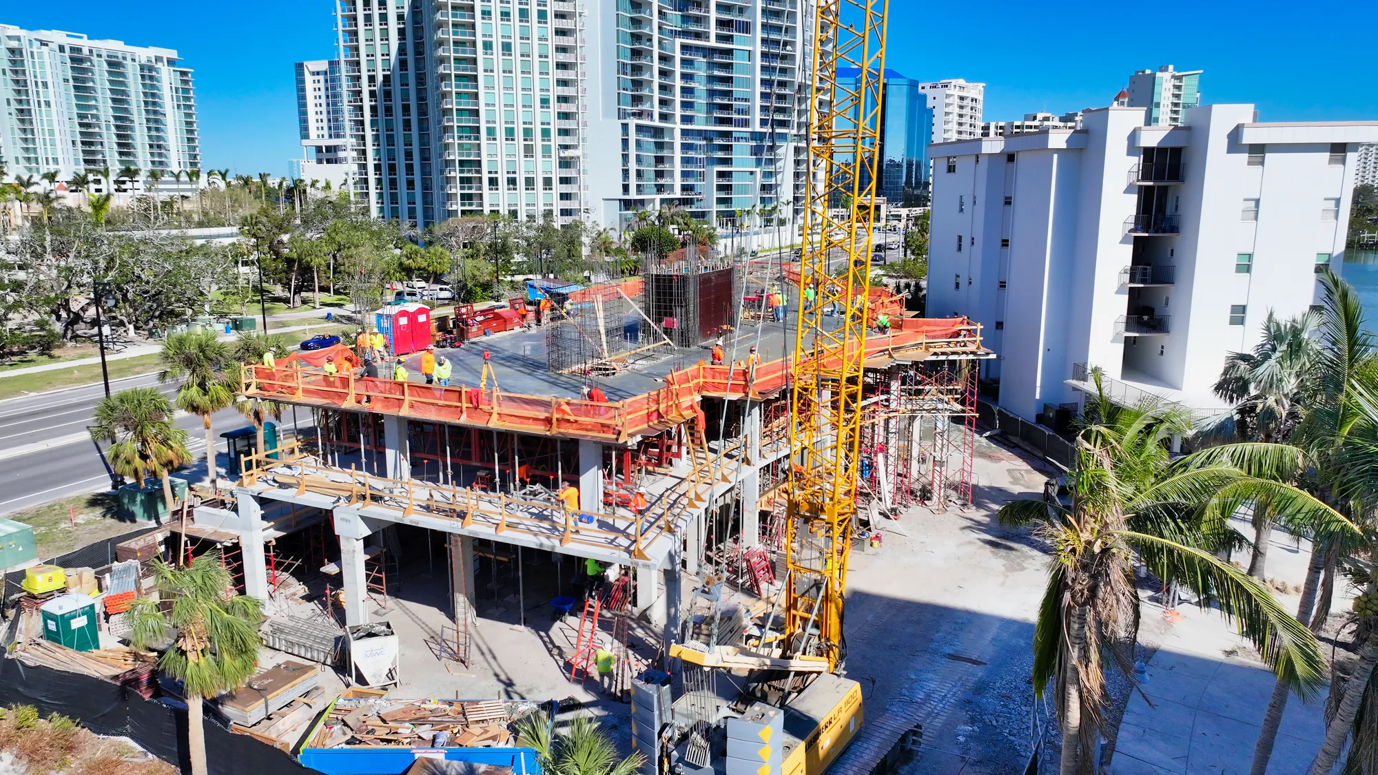 Commercial construction crew working beside scaffolding and a large crane on an active high-rise project.