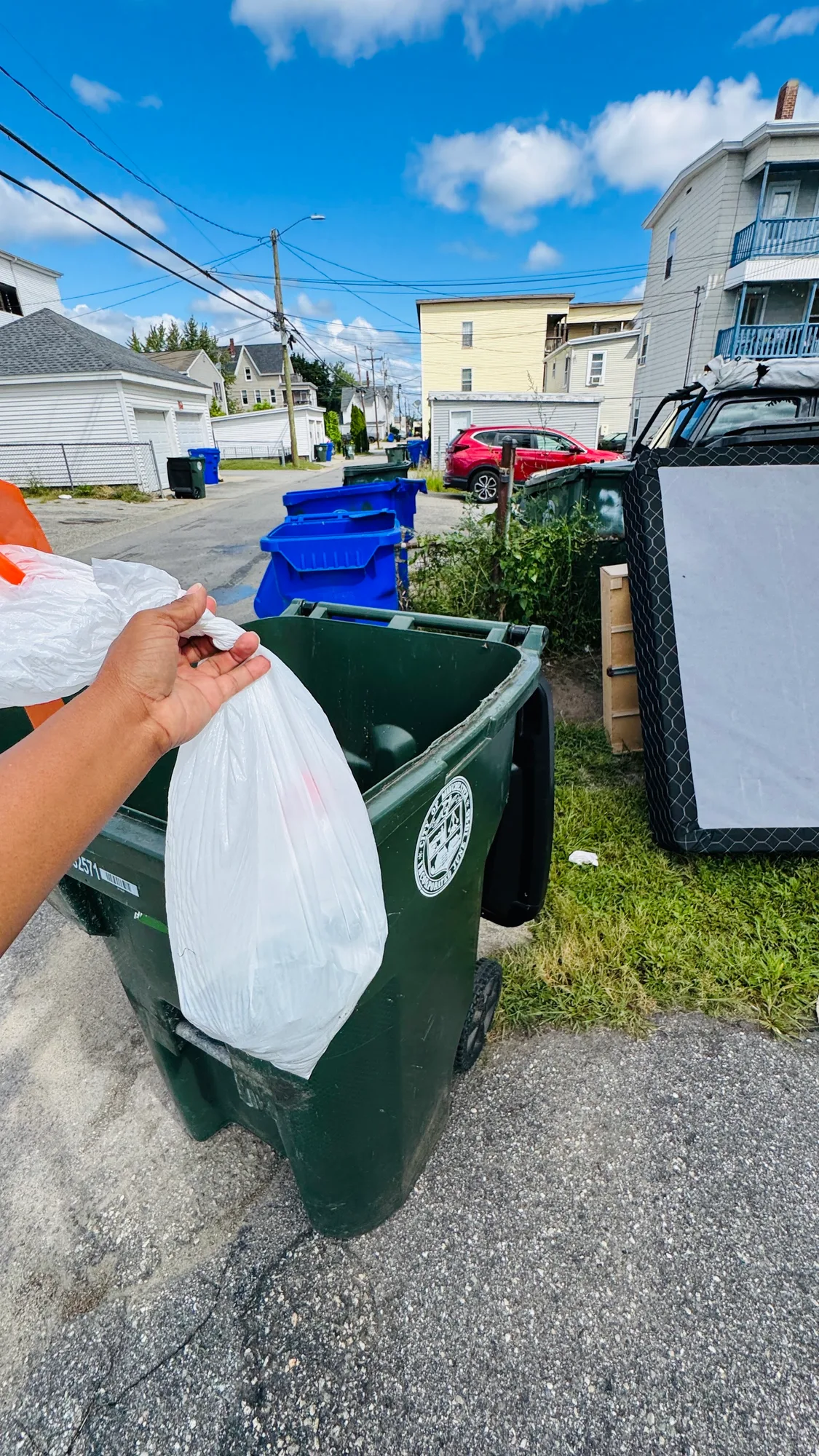 Double-bagged pet waste being placed into a customer's outdoor trash barrel at the curb